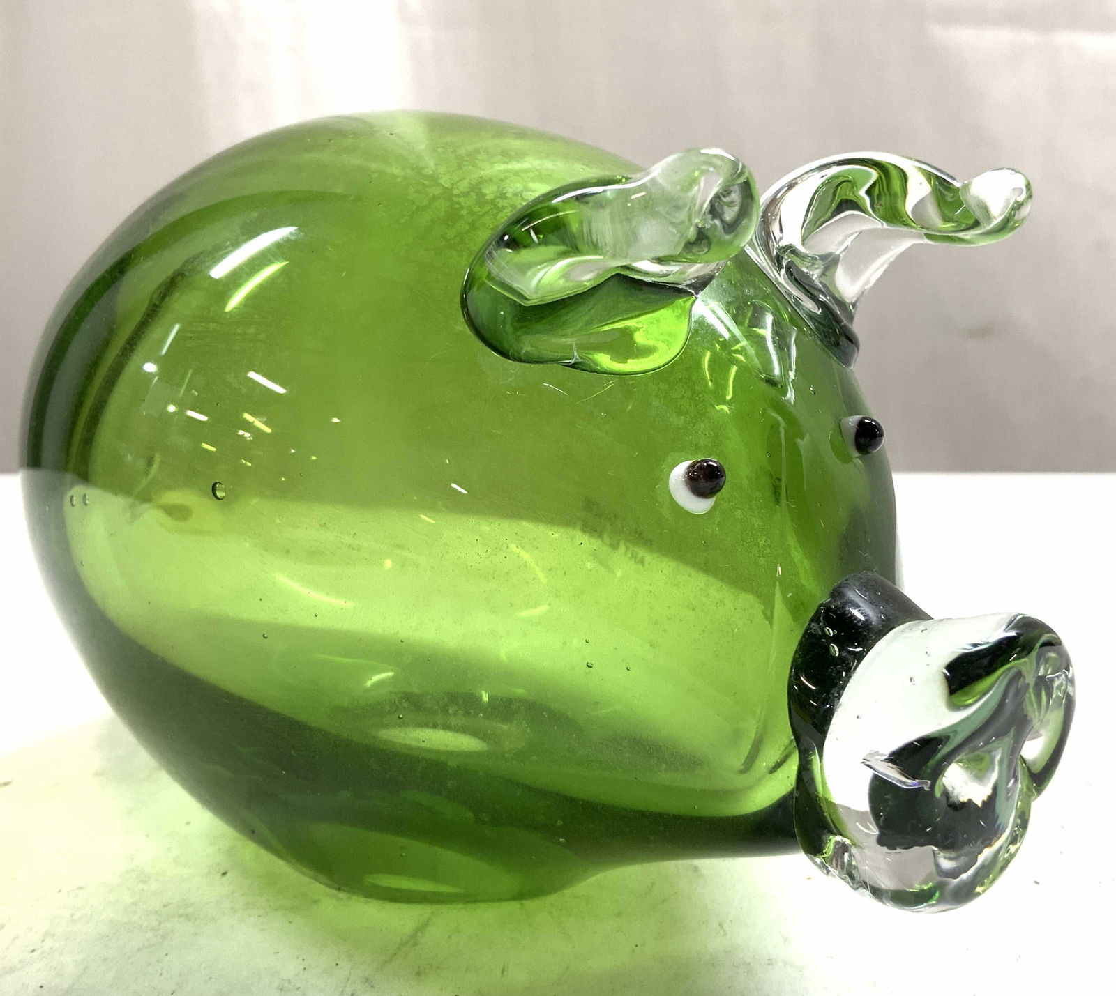 Hand Blown Art Glass Pig Figure Green: Tag reads HANDMADE ART GLASS. Pig figure is green toned with clear ears and snout. Piece appears to be crafted from hand blown glass due to hole on underside. Figure measures approximately 6 inches de