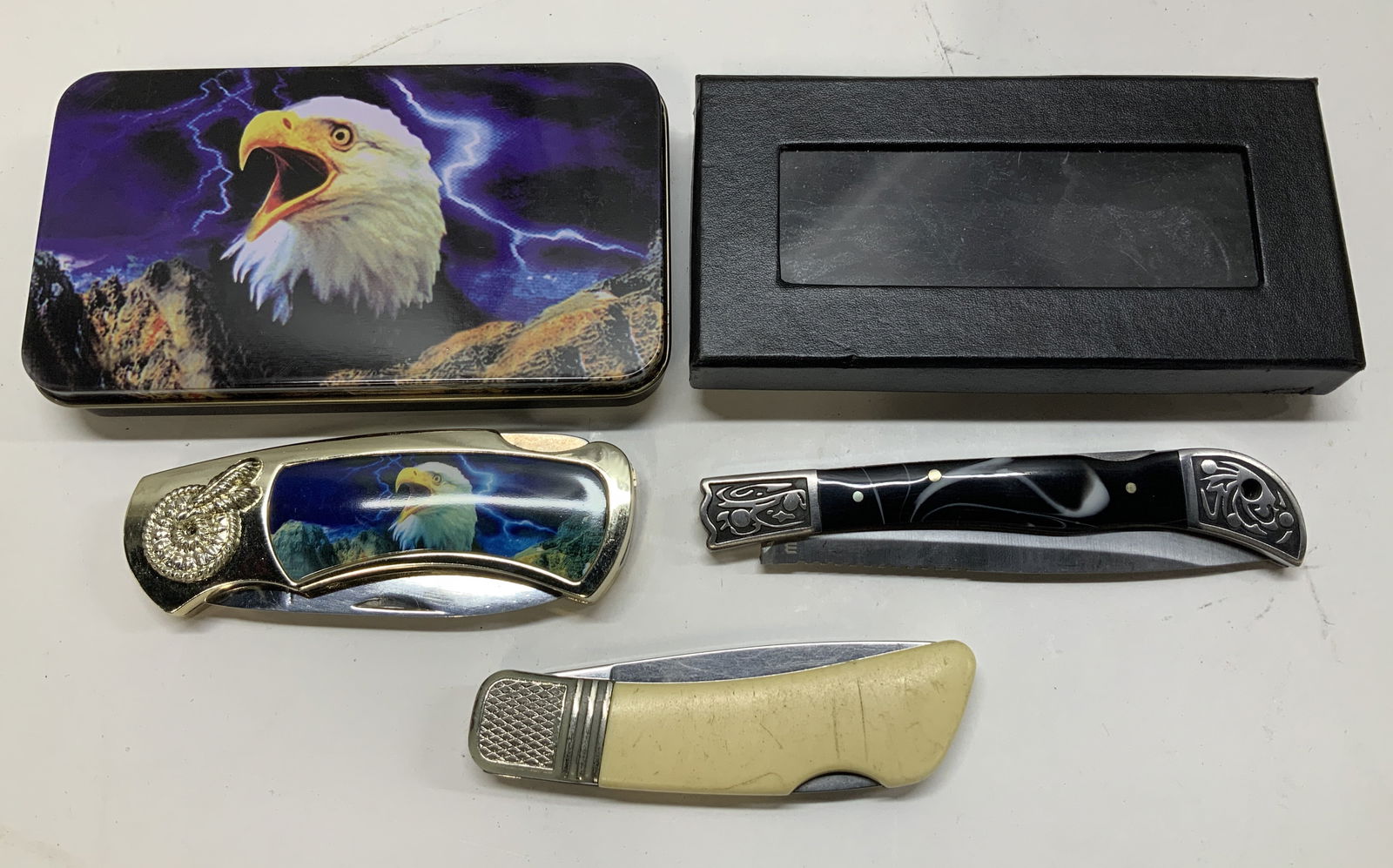 Lot 3 Assorted Stainless Steel Pocket Knives SABRE: Lot includes, 3 stainless steel pocket knives. Pieces feature different designs on handles. Possible bone handle, white swirl design & eagle motif. Signed & marked. 1 knife reads, SABRE STAINLESS. Kni
