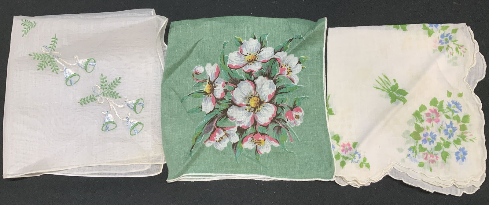 Lot 3 Vntg Assorted Floral & Bells Handkerchiefs: Handkerchiefs appears to be possible linen or cotton material. They feature floral patterns in shades of pink, white, green & blue. 1 handkerchief features a scalloped edge. 1 handkerchief features an