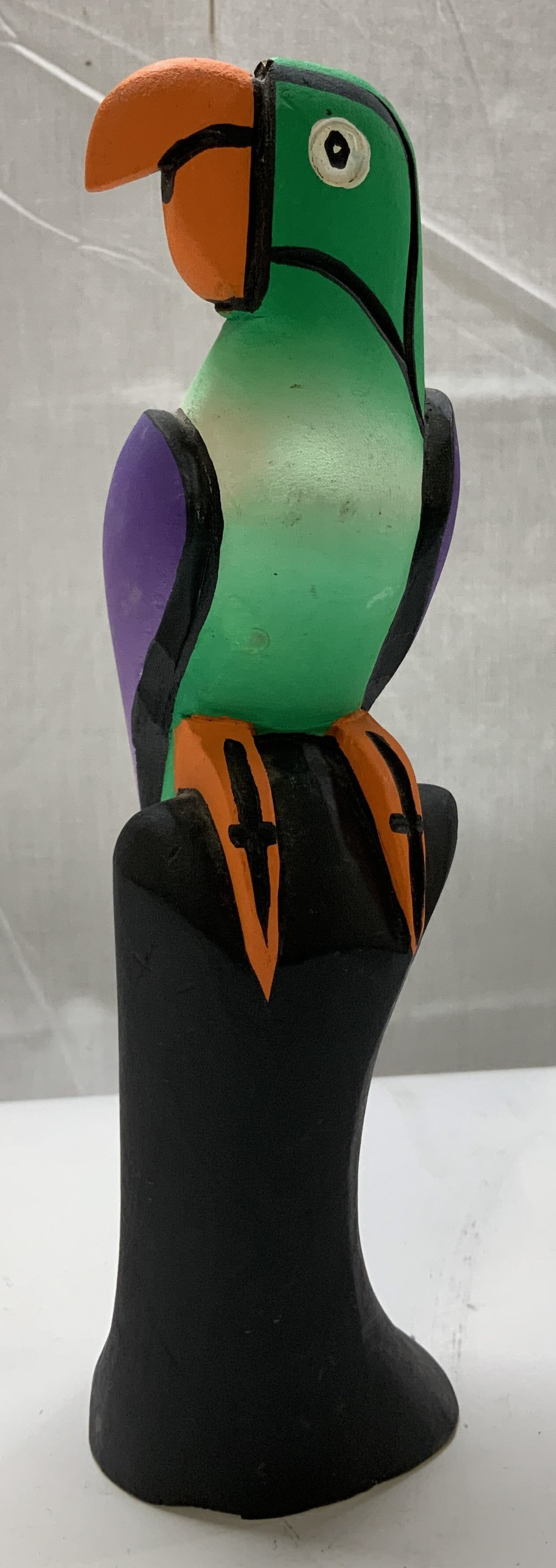 Piuani Hand Carved Wooden Parrot Figurine MEXICO: Carved wooden parrot, painted in vibrant colors. Parrot is perched on a black cylindrical base. Hand-painted & hand-carved details. Signed & marked on underside. Reads, PIUANI. MEXICO. Surface wear co