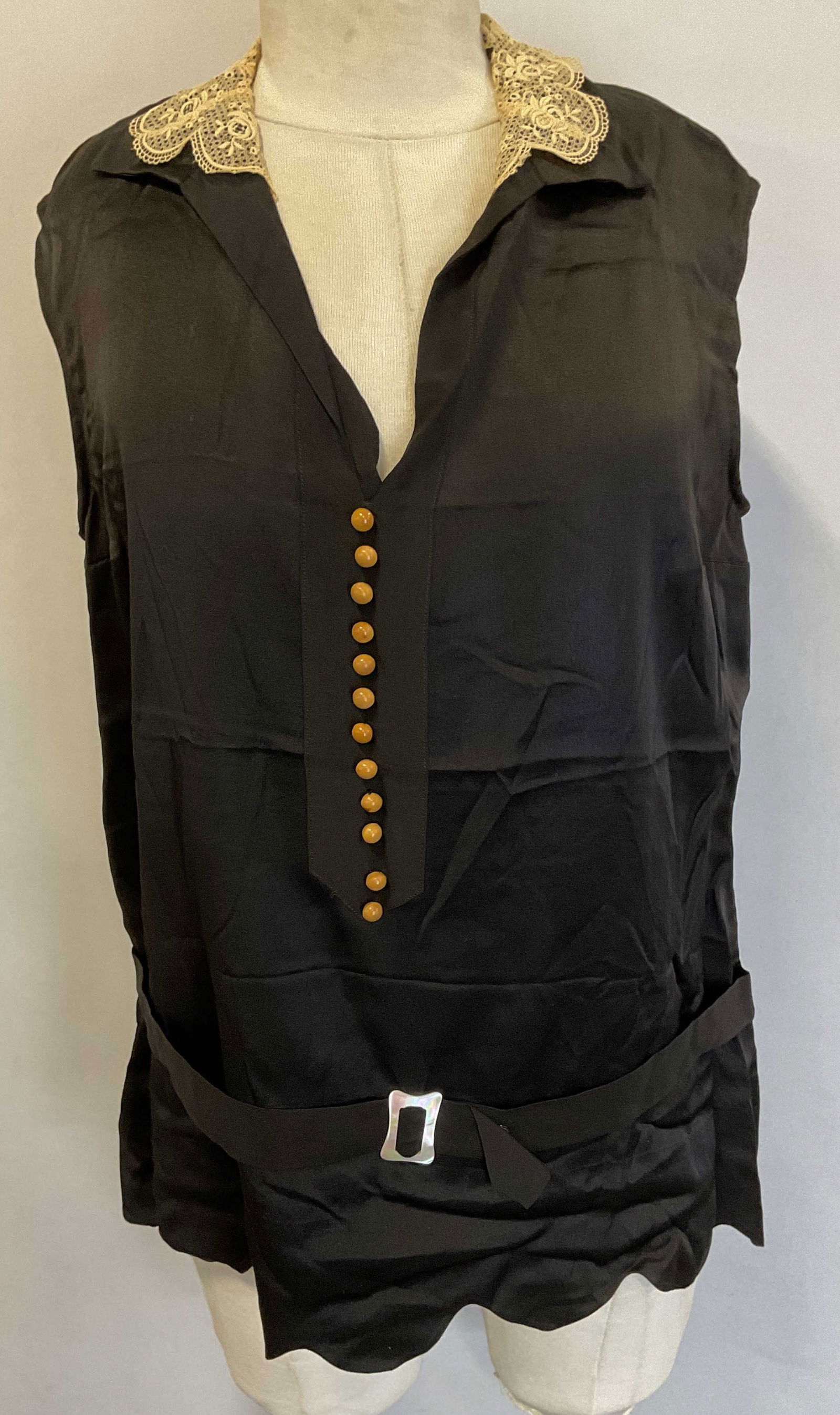 1920s Black Silk Sleeveless Lace Collar Top: Vintage c. 1920s black silk sleeveless top with lace collar, faux button, and belted waist with mother of pearl buckle. Measures approx 18 inches across chest. Some discoloration, tearing on shoulder