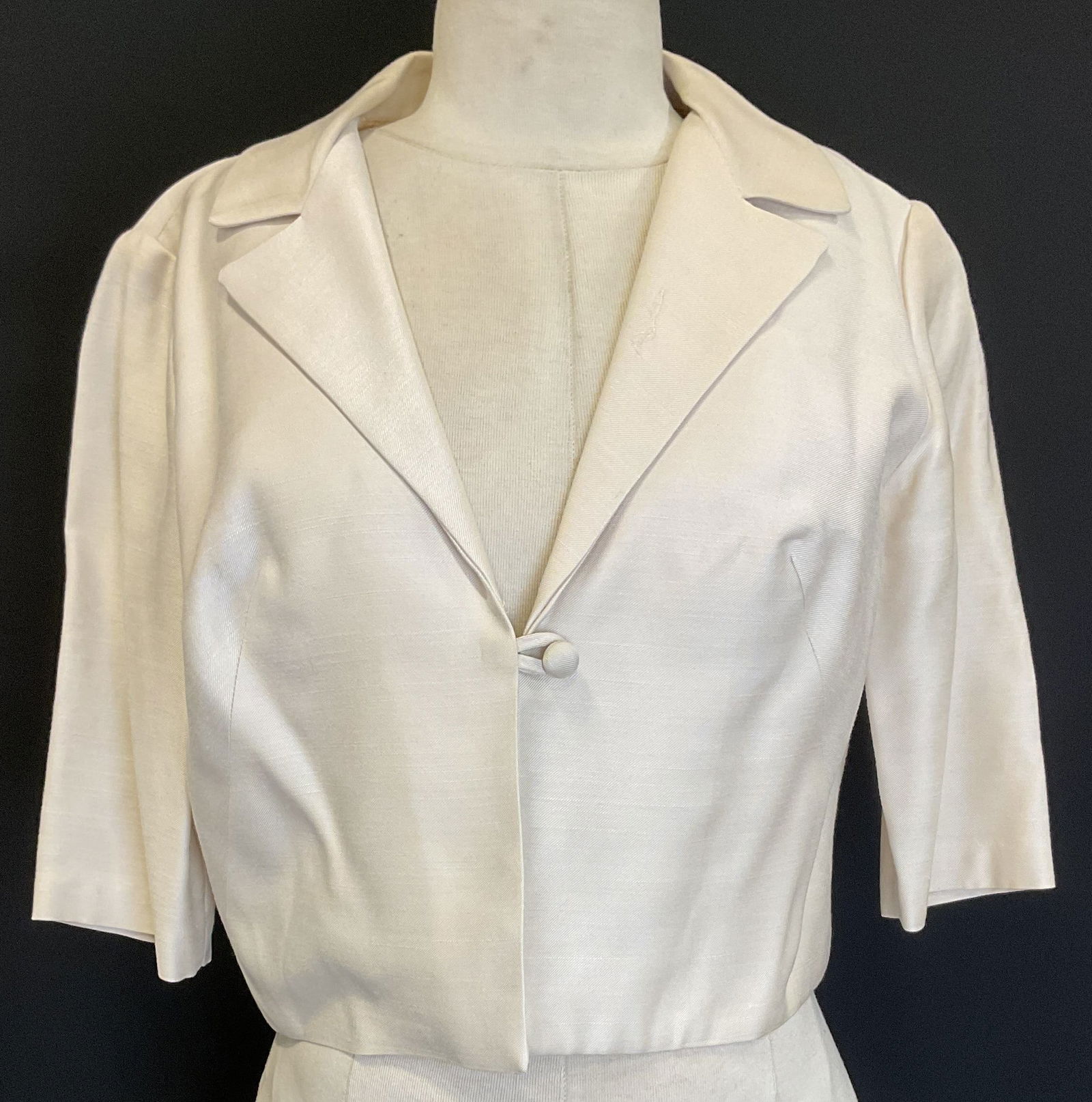 Vtg White Silk Cropped Blazer: Vintage white silk cropped blazer. Lapel collar and one button. 19 inches across chest. 17.5 inches long. Some surface wear consistent with exposure, slight tearing on inside sleeves, loose thread and