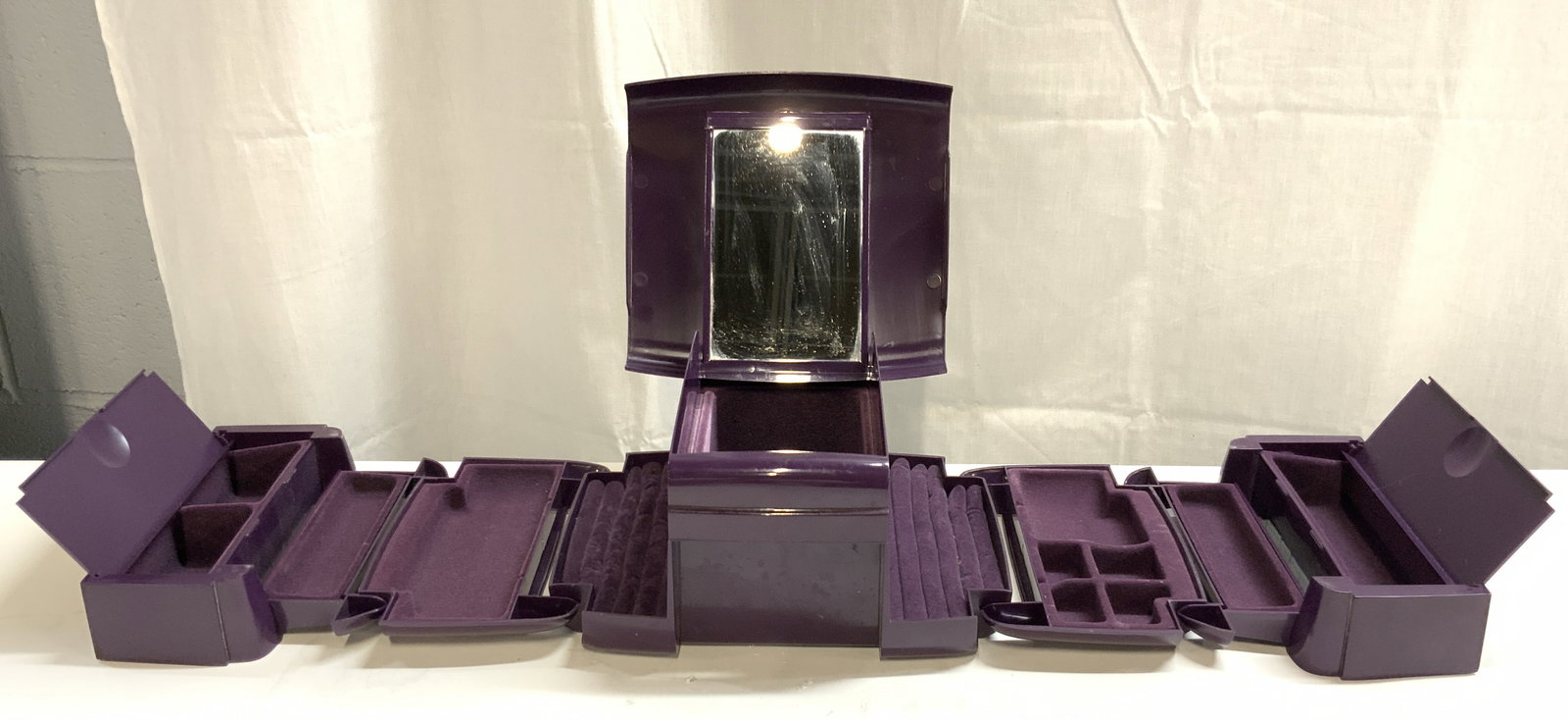 INGENIOUS DESIGNS The Jewel Kit Purple USA: Underside reads INGENIOUS DESIGNS LLC THE JEWEL KIT. Jewelry box is purple toned and plastic. Piece has numerous folding compartments. Sides and main compartments have lids. Underside of main area lid