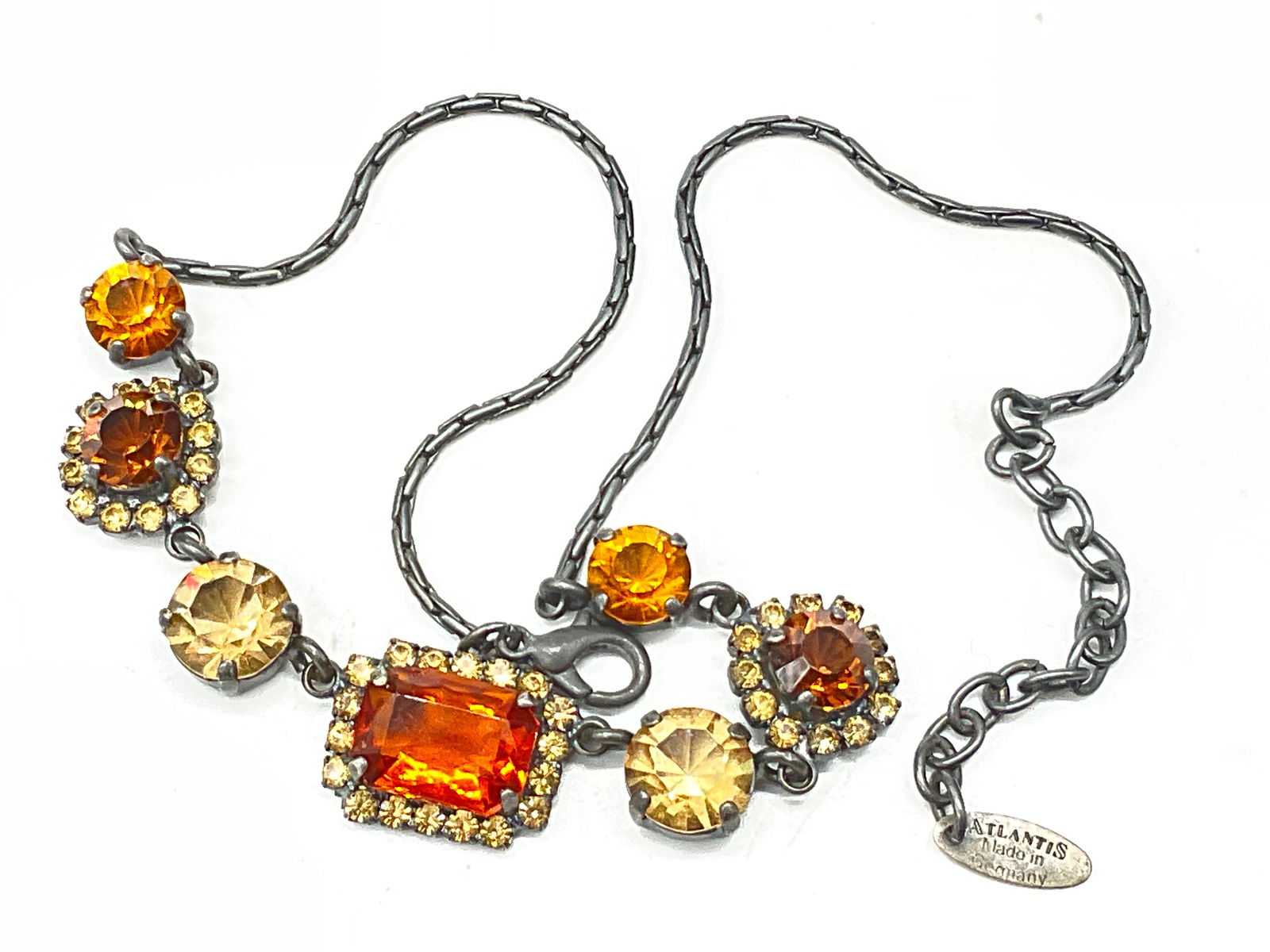 ATLANTIS GERMANY Faceted Amber Rhinestone Necklace: ATLANTIS GERMANY Faceted Costume Amber Rhinestone Necklace. Necklace length measured end to end approx. 16 inches. Charm adjacent to the lobster clasp closure reads ATLANTIS MADE IN GERMANY. Surface w