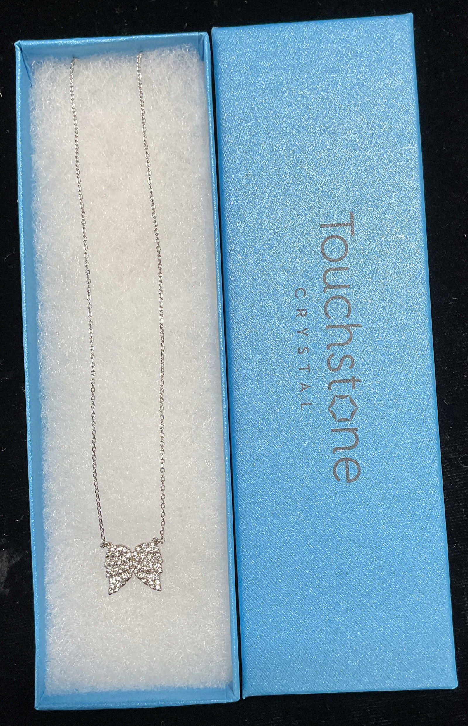 Swarovski Touchstone Crystal Angel Necklace NIB: Touchstone by Swarovski silver tone necklace with crystal angel wings pendant. Signed. New in box. Drop length approx 8.75 inches. Some scratching. Jewelry, estate jewelry, costume jewelry, cocktail j
