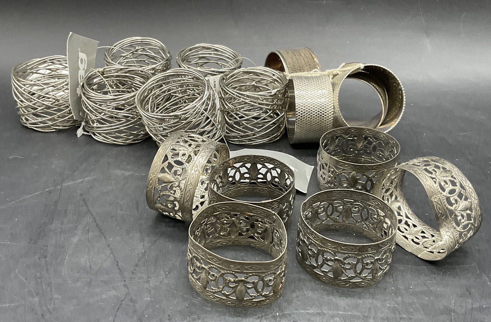 16 Vintage Silver Tone Metal Napkin Ring Sets Tag+: Sixteen Vintage Silver Tone Metal Napkin Rings. Some feature open metalwork designs, wire wrapping, or etched metalwork. Some pieces have their original tags attached which read TAG, these measure app