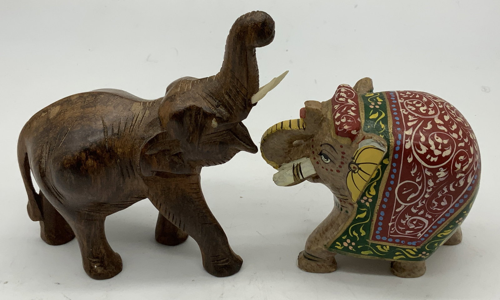 Lot 2 Carved Wooden & Stone Elephant Figurines: Lot includes, 1 hand-carved wooden elephant figurine & 1 carved hard stone Indian elephant. Elephant features intricate pattern & vibrant tones. Surface wear consistent to age, use & exposure. Measure