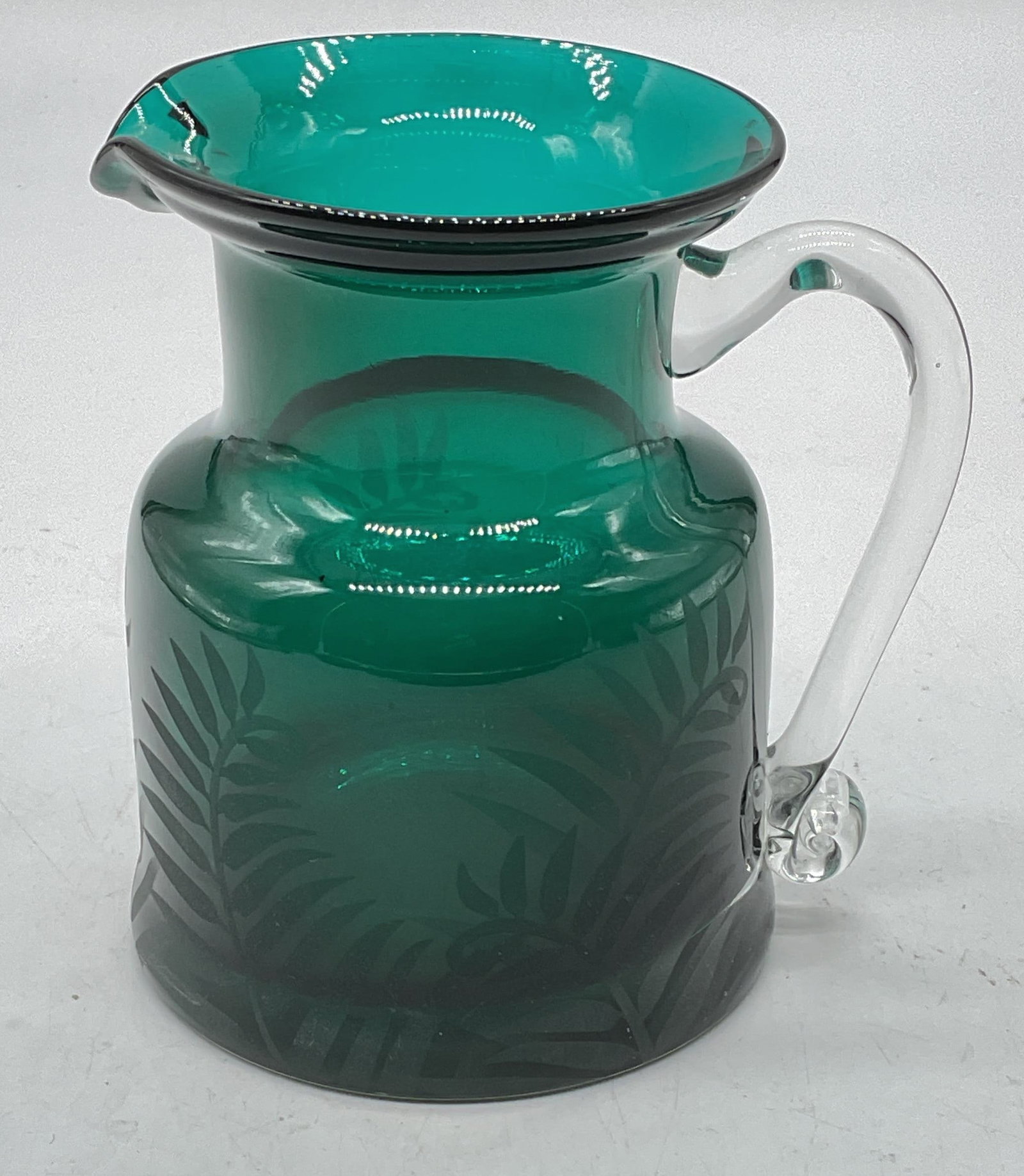 Signed Green Art Glass Botanical Pitcher: Signed green art glass pitcher with applied handles and botanical design. Signed on underside. Measures approx 3.5 x 4.5 inches. Some wear consistent with exposure. Art glasses pitcher, green pitcher,