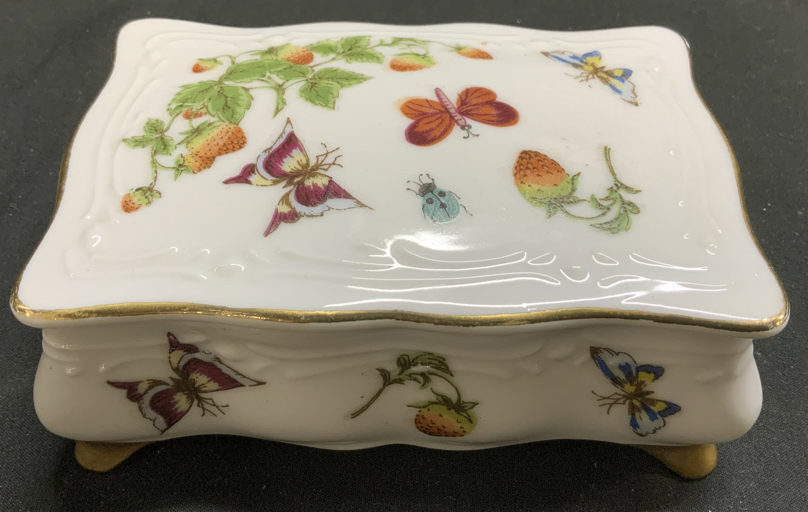 Vntg Hand Painted Butterfly Porcelain Trinket Box: Trinket box is porcelain material. Features hand-painted butterfly, strawberry & insect motifs. 4 gilt feet. Marked on underside. Reads, 6177. Surface wear consistent to age, use & exposure. Measureme