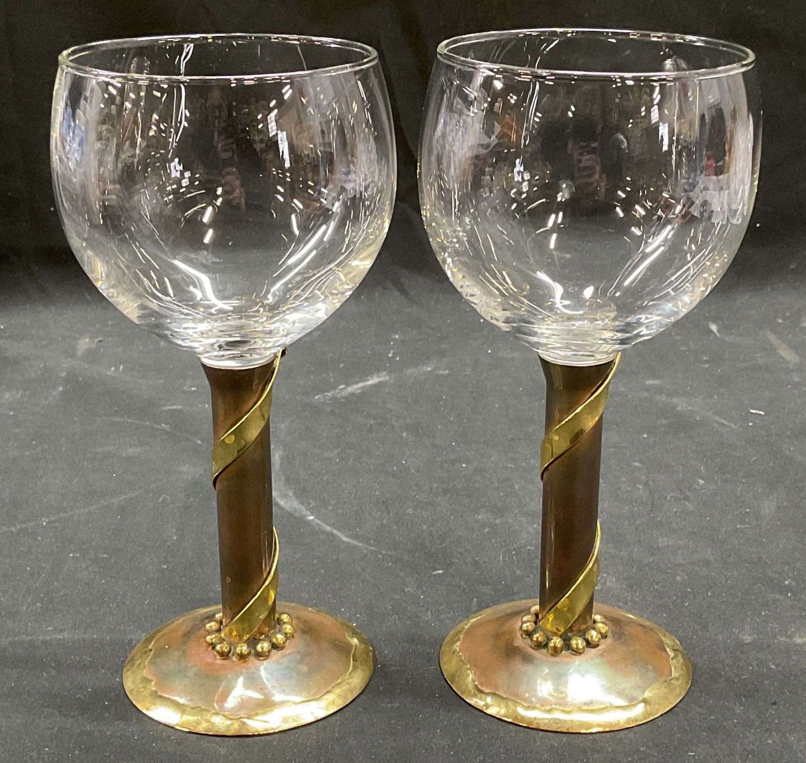 Pr Signed MM Brass & Copper Stem Wine Glasses 2003: Pair of handcrafted wine glasses with brass and copper stems. Signed and dated on undersides, MM 2003. Made in USA. Measures approx 3.25 x 7 inches. Some patina and scratching. Wine glasses, copper st