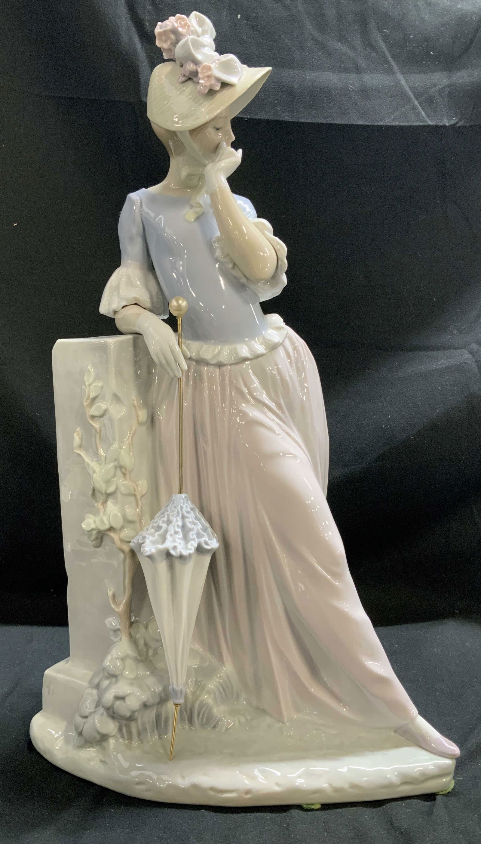 Vntg LLADRO Woman W Umbrella Large Porc Fig SPAIN: Large porcelain figurine depicting a woman wearing a floral hat, leaning against a porcelain column. Right hand is holding an umbrella. Glossy finish. Surface wear consistent to age, use & exposure. V