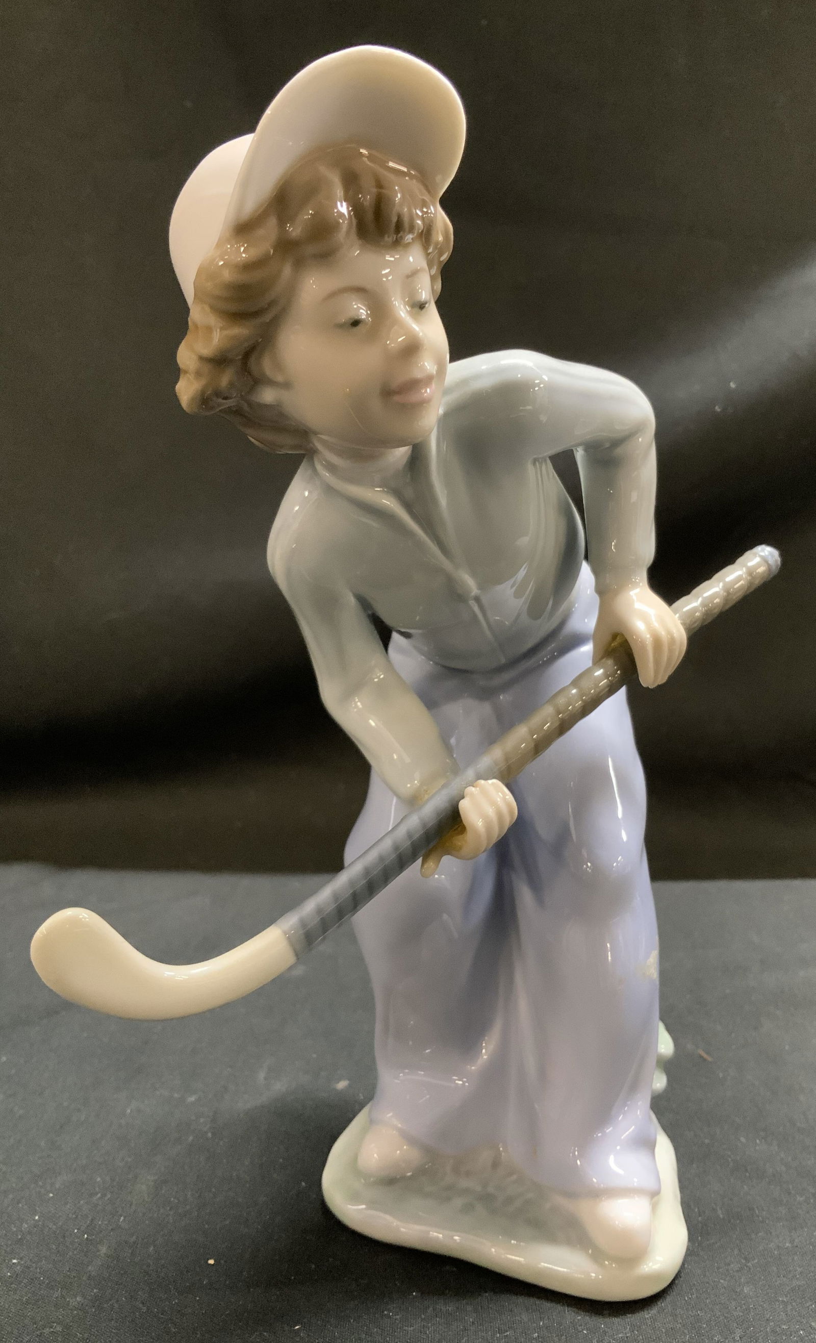 LLADRO NAO Hockey Player Porc Figurine SPAIN 1986: Depicts a young boy holding a hockey stick. Boy is wearing a white cap & is in a crouching stance. Piece is hand made & features a glossy finish. Surface wear consistent to age, use & exposure. Signed