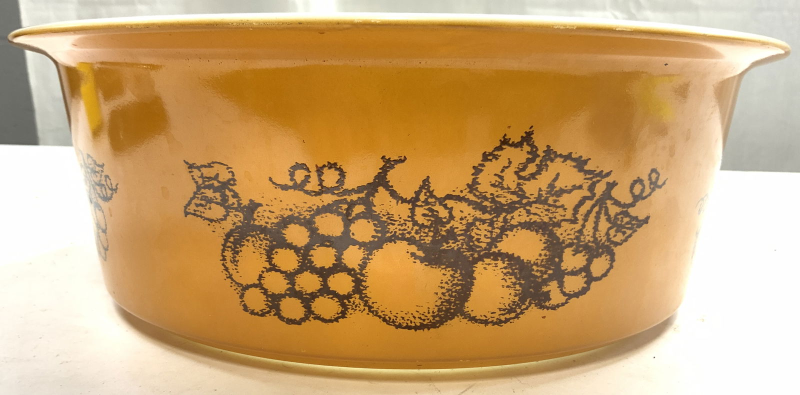 PYREX BY CORNING Old Orchard Big Bertha Cass Dish: Underside reads PUREX BY CORNING. Casserole dish is vintage circa 1970s. Old Orchard Big Bertha Casserole dish. Exterior is orange with brown toned fruit and leaf detail. Interior is white toned. Dish