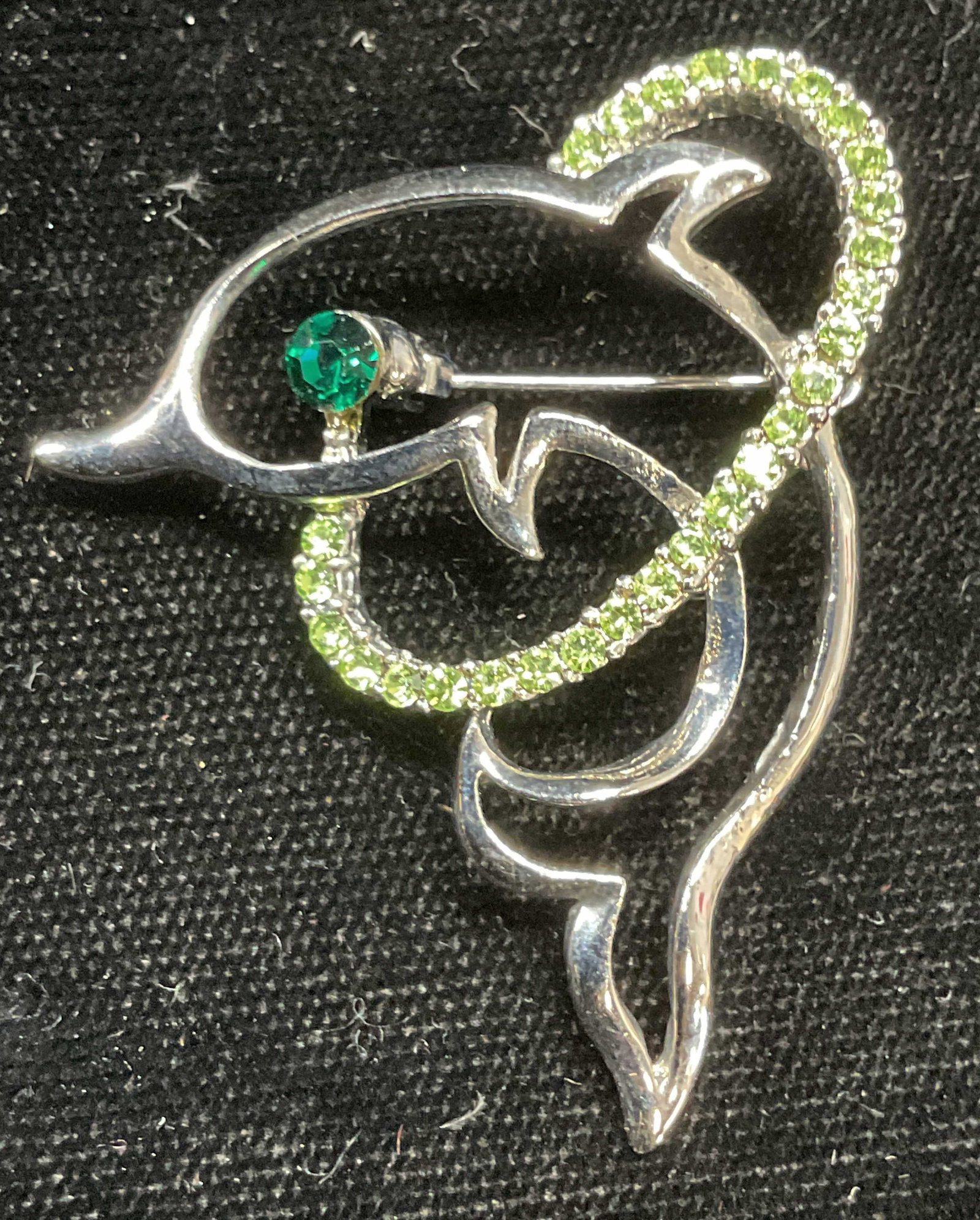 Silver Tone Green Crystal Dolphin Brooch: Silver tone dolphin brooch with green crystal decoration. Measures approx 1.75 x 1.5 inches. Some wear including scratching observed. Jewelry, estate jewelry, costume jewelry, cocktail jewelry, fashio
