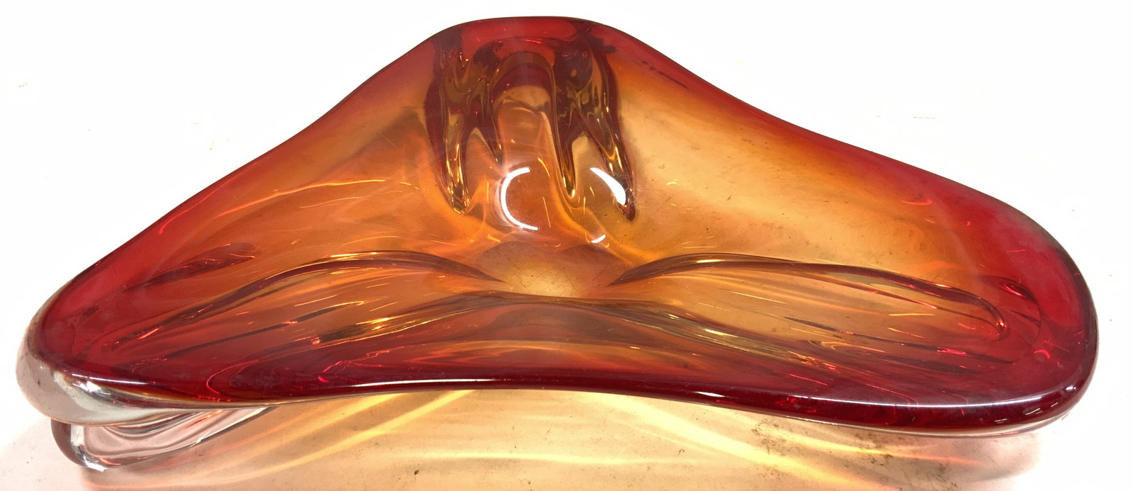Vntg Hand Blown Triangular Amberina Glass Bowl: Bowl is glass. Piece has triangular form. Amberina glass bowl with red to orange toned gradient. Bowl is vintage. Piece has clear feet. Piece appears to be hand blown/ hand crafted. Bowl measures appr