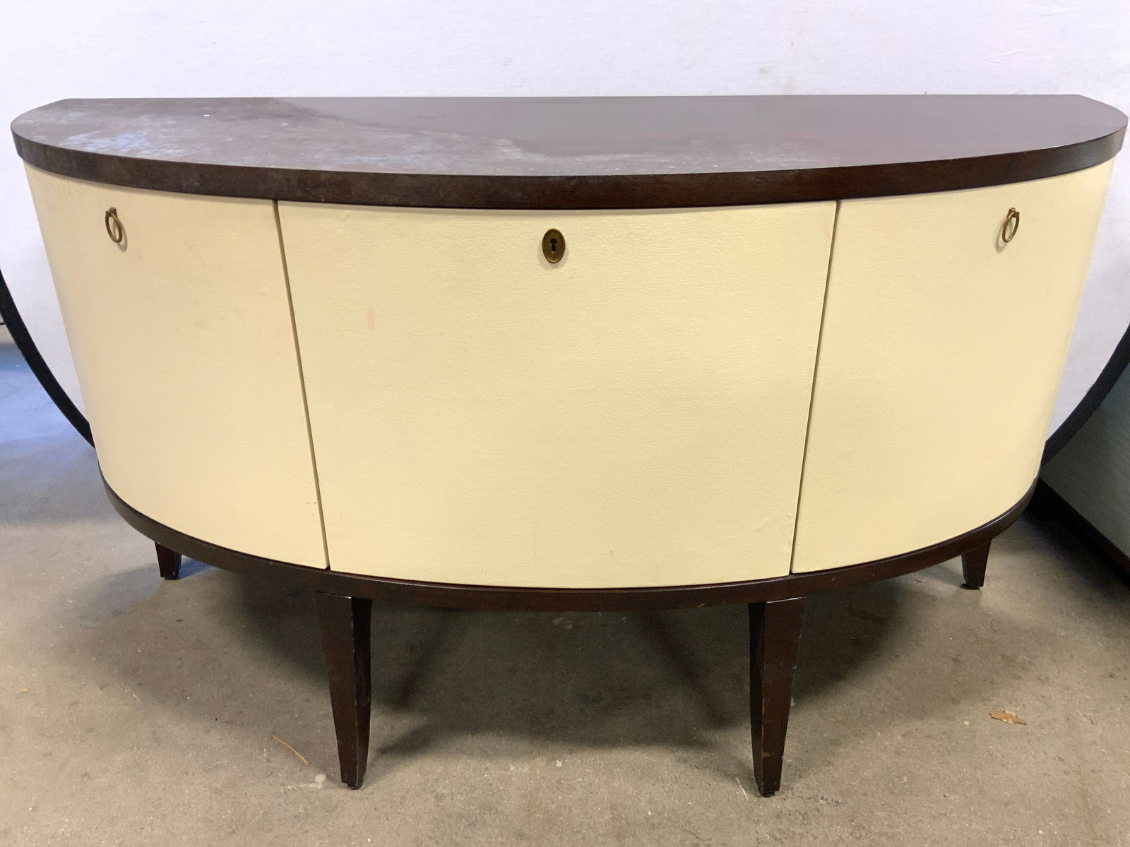 BLOOMINGDALES The Oval Coll Linen Console: BLOOMINGDALES Console part of the oval collection. Brown toned Dark walnut with cream toned cabinet doors. Interior of each cabinet has 1 wooden shelf. Doors appear to be lined in linen. Piece has Gil