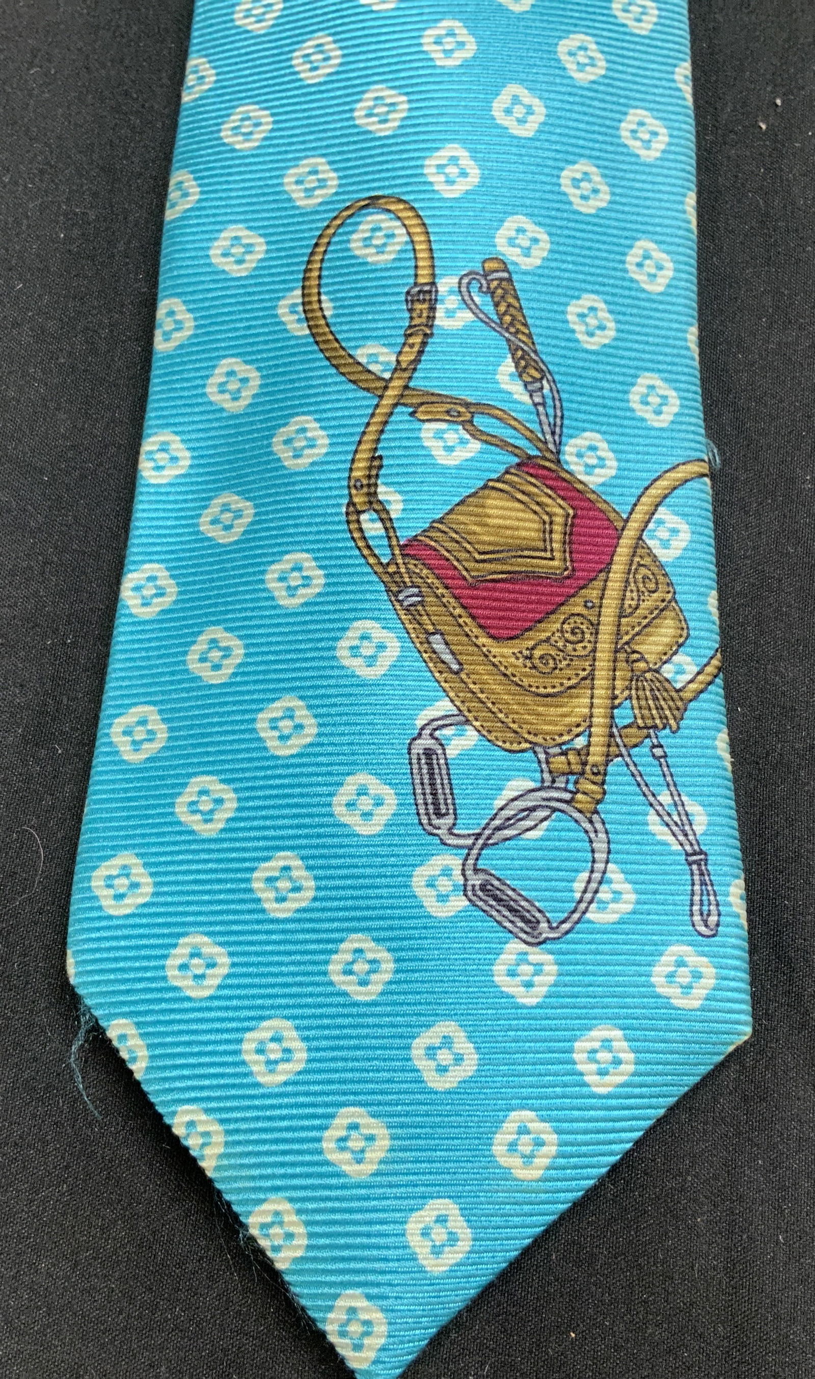 Images Guy Laroche Equestrian Motif Silk Tie: Tie is 100% silk material & features a stylized saddle with stirrups. Light blue patterned background. Signed & marked. Reads, IMAGES GUY LAROCHE. Surface wear consistent to age, use & exposure. Measu