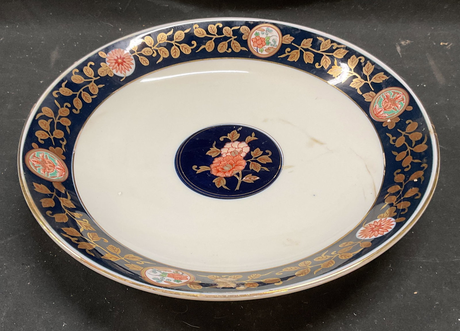 Signed Japanese Arita Ware Porcelain Bowl: Signed Japanese Arita Ware porcelain bowl. Cobalt blue center and rim with hand painted floral pattern with gilt accents. Measures approx 10.75 x 1.75 inches. Some scratching and loss to paint. Arita 