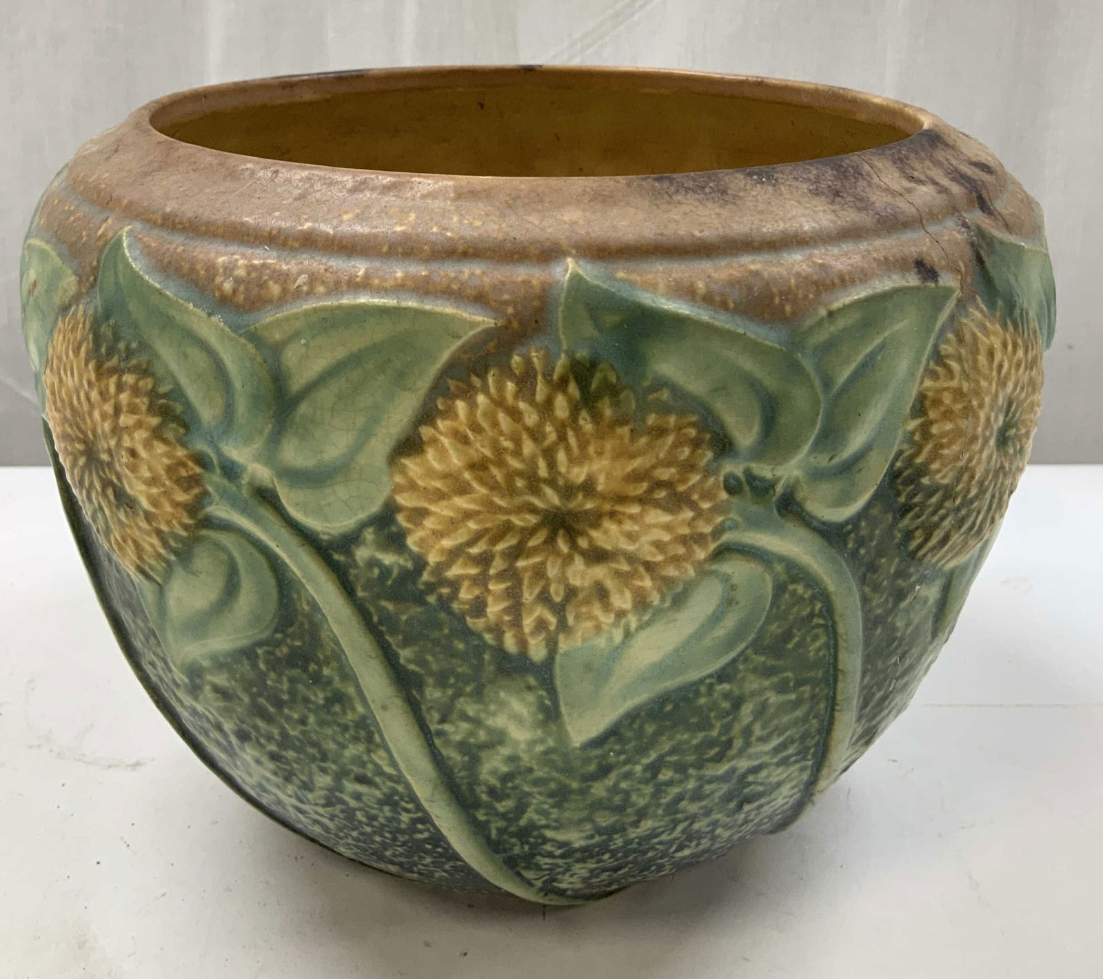 Vintage Sunflower Ceramic Jardiniere: Jardiniere is ceramic & features raised sunflowers motifs. Yellow & green tones. Piece is textured & has intricate detailing. Surface wear consistent to age, use & exposure. Visible cracking. Measurem