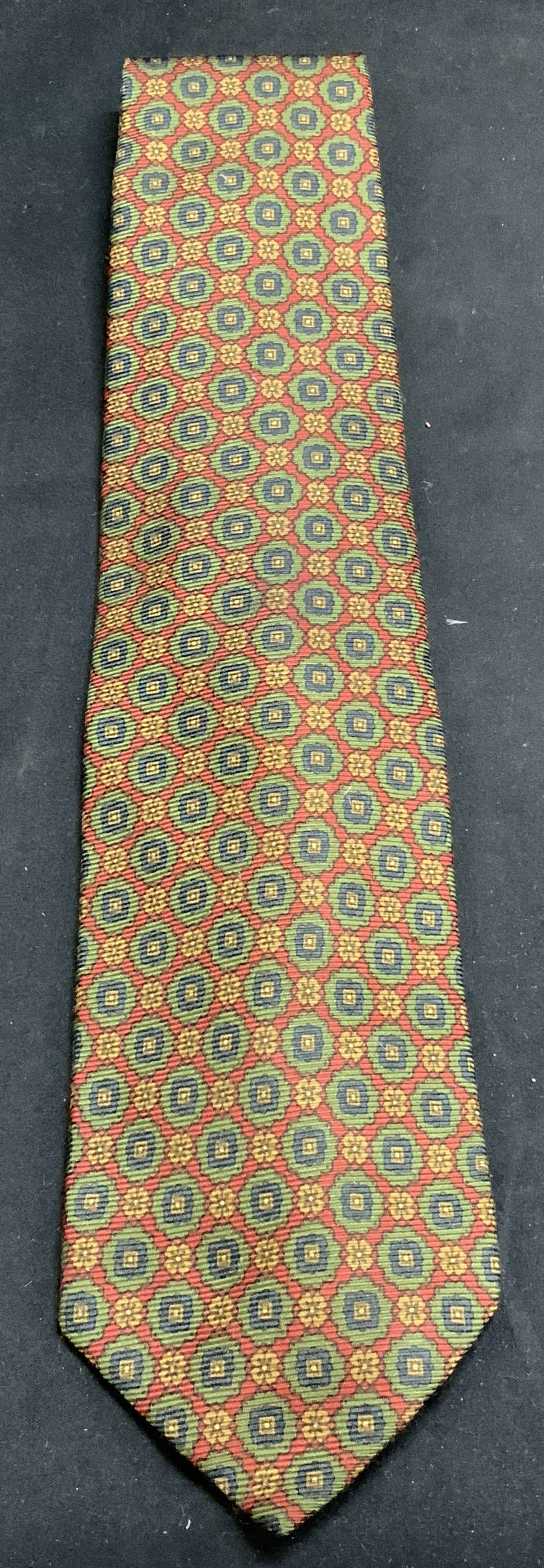 SULKA Red & Green Geometric Silk Necktie FRANCE: Necktie is silk & features small floral like motifs. Green, red & yellow tones. Signed & marked. Reads, SULKA. MADE IN FRANCE. SILK. Surface wear consistent to age, use & exposure. Measurements: lengt