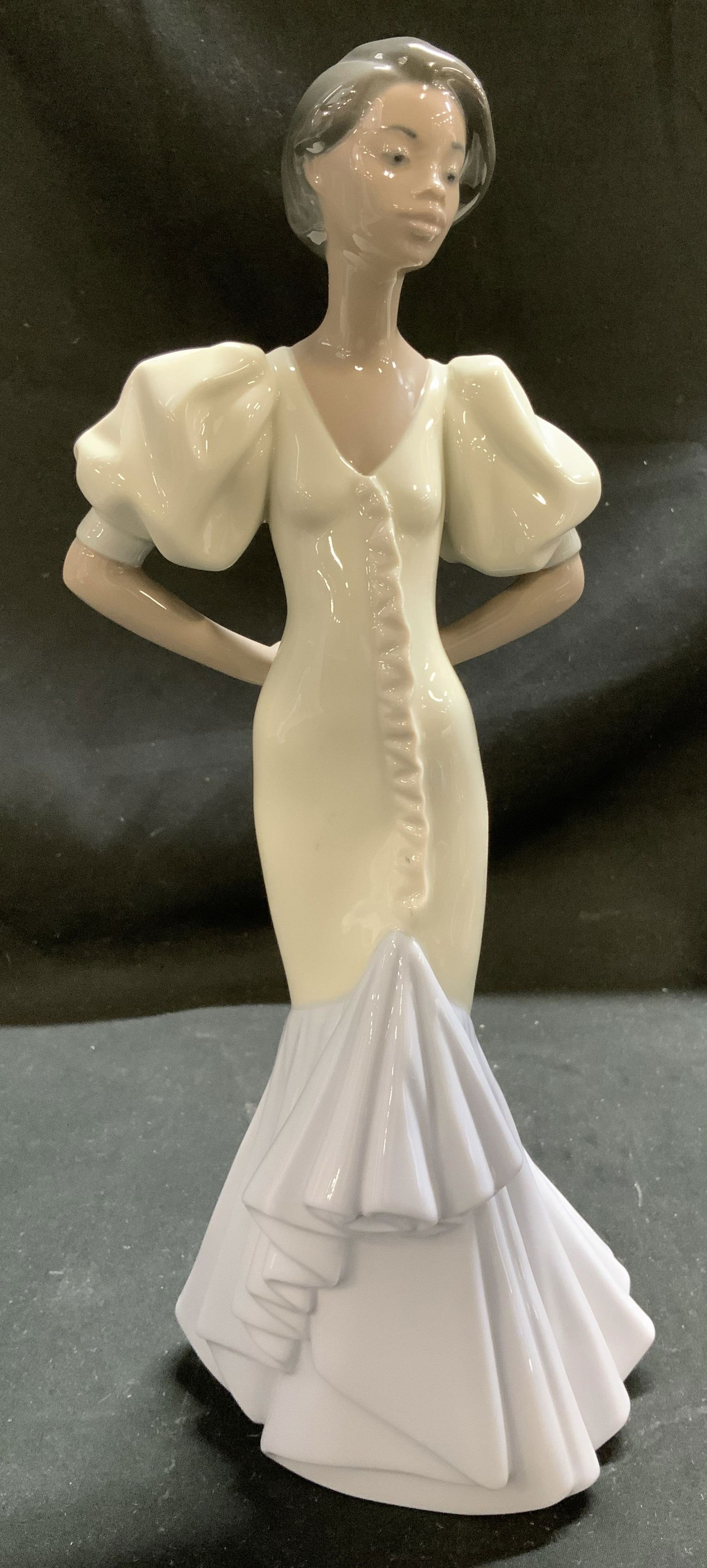 Lladro Velisa Hand Made Porcel Figural SPAIN 1994: Figurine depicts a woman wearing a dress with puffed sleeves. Her hands are clasped behind her back. Glossy finish. Signed & marked on underside. Reads, LLADRO HAND MADE IN SPAIN. DAISA 1994. Surface