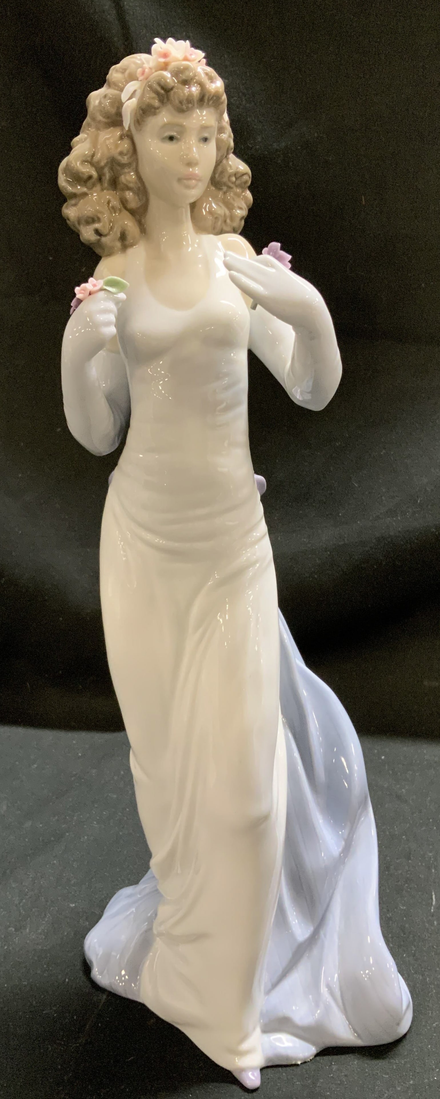 Lladro 1999 Anticipation Exclusive Porc Fig SPAIN: Figurine depicts a young woman in a long, flowing white gown. Woman has wavy brown hair & is holding flowers in her hands. Glossy finish. Signed & marked on underside. Reads, LLADRO 17 EPP. HAND MADE