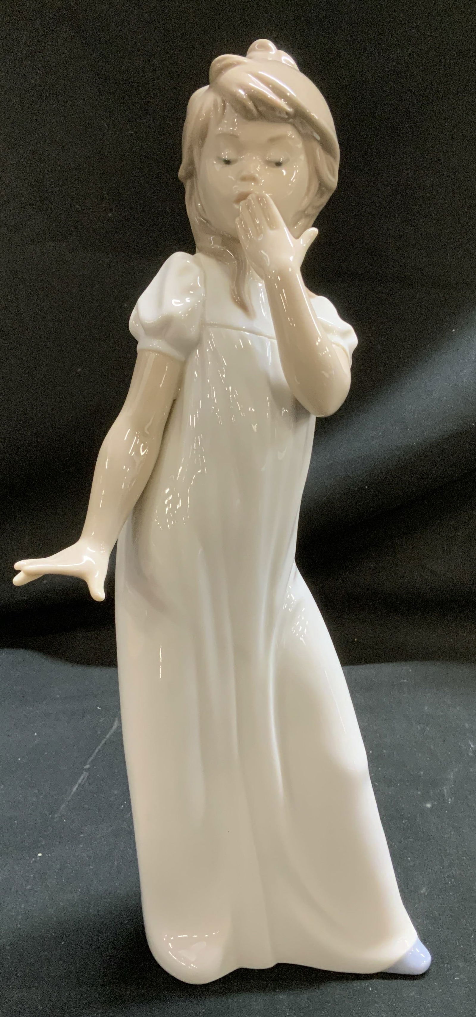 NAO Lladro Girl Yawning Porcelain Figurine SPAIN: Figurine depicts a young girl in a white nightgown. She is yawning, with one hand raised to cover her mouth. Glossy finish. Signed & marked on underside. Reads, NAO HAND MADE IN SPAIN BY LLADRO. DAISA