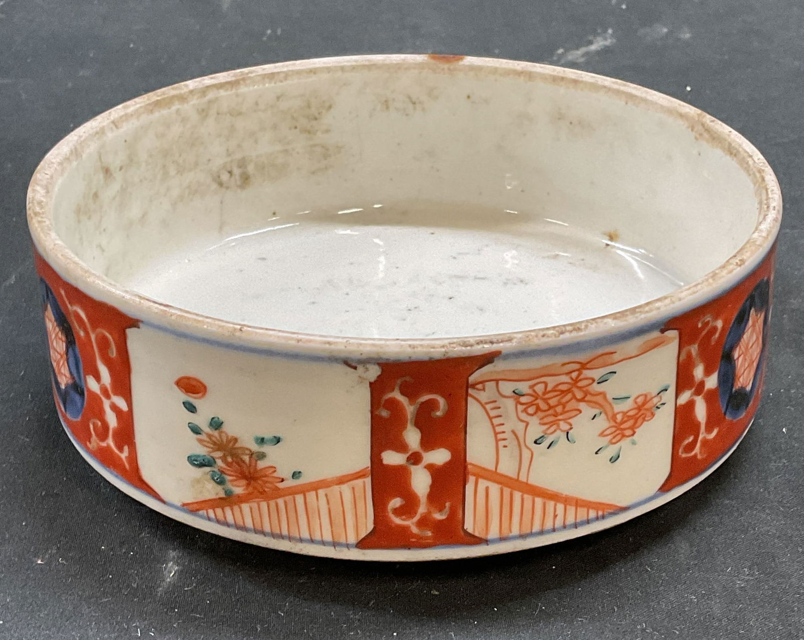 Antique Japanese Imari Porcelain Bowl: Antique Japanese Imari porcelain bowl. Hand painted in blue and red with cartouches of traditional style floral botanical designs. Measures approx 6 x 2.25 inches. Wear including scratching, loss to p