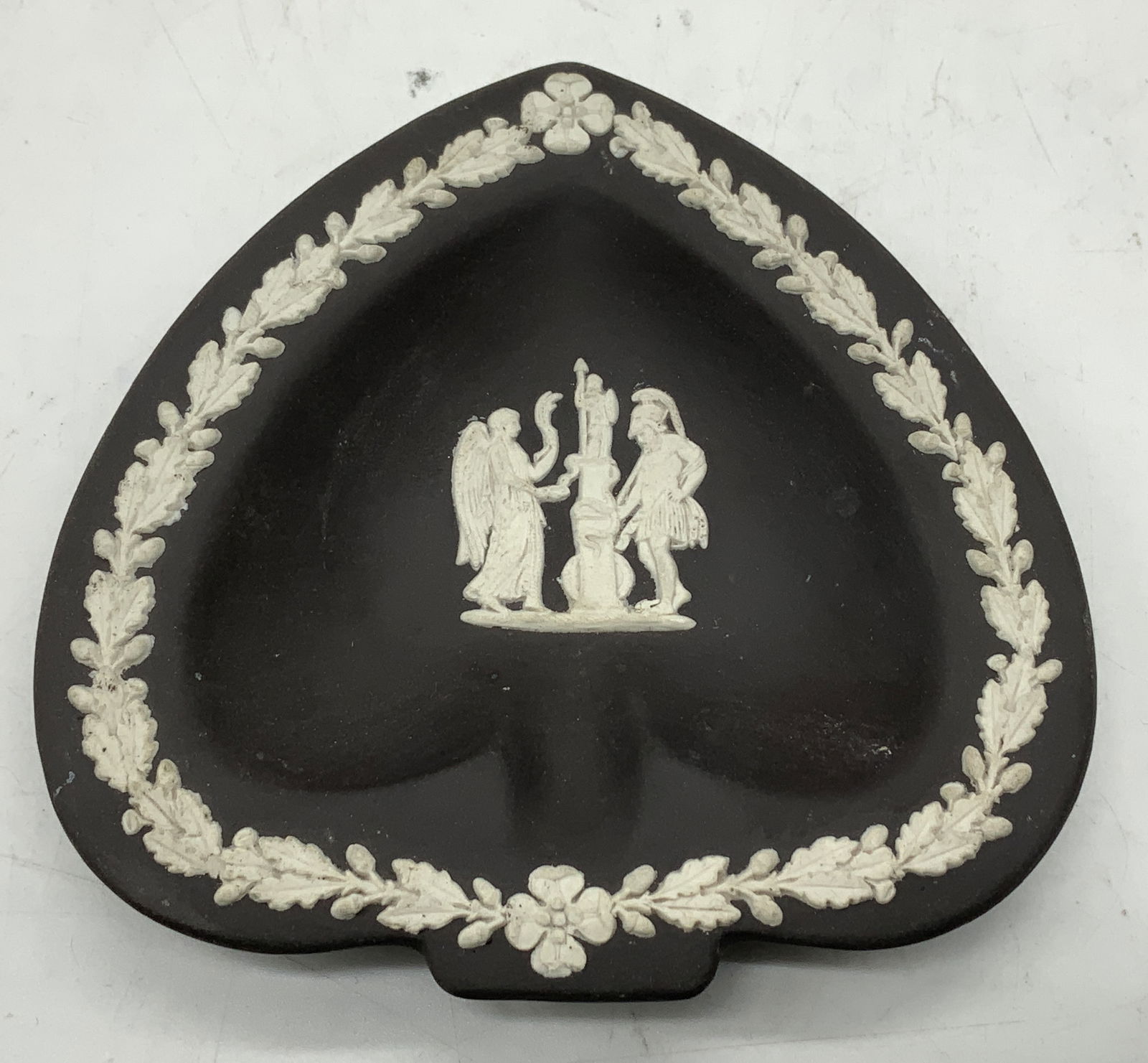 Wedgwood Black Jasperware Heart Ashtray ENGLAND: Black Wedgwood Jasperware ashtray has a heart shape, adorned w a central white neoclassical relief surrounded by a raised foliate border. Surface wear consistent to age, use & exposure. Measurements: