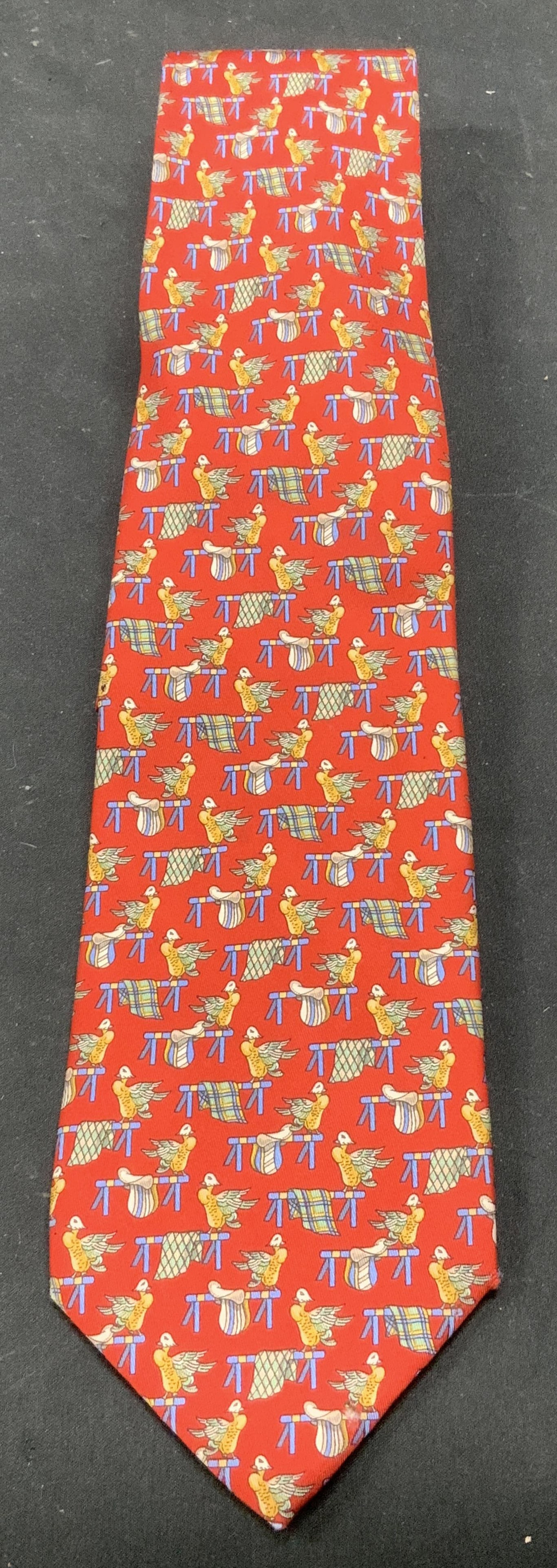 Salvatore Ferragamo Stylized Ducks Silk Tie ITALY: Necktie is silk & features a repeating pattern of small, stylized ducks in yellow and green hues. Red background. Surface wear consistent to age, use & exposure. Measurements: length 57in x width 3.5i