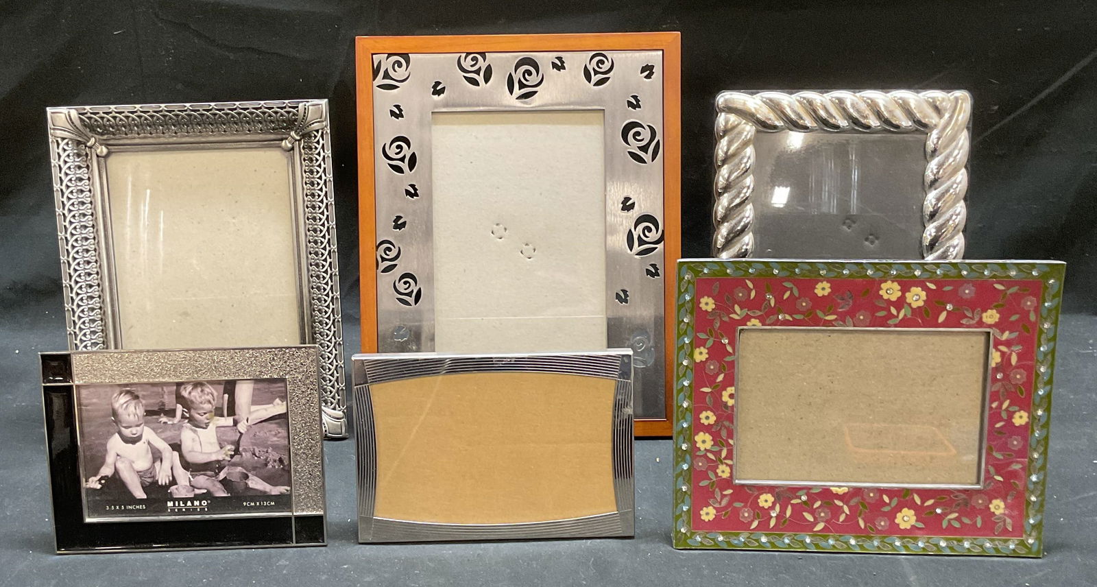 Lot 6 Milano Home+ Decorative Picture Frames: Lot of 6 decorative picture frames. Milano Home Striped silver tone frame and silver tone and black enamel frame. Silver tone scroll frame, silver tone cable frame, wood and silver tone pierced flower