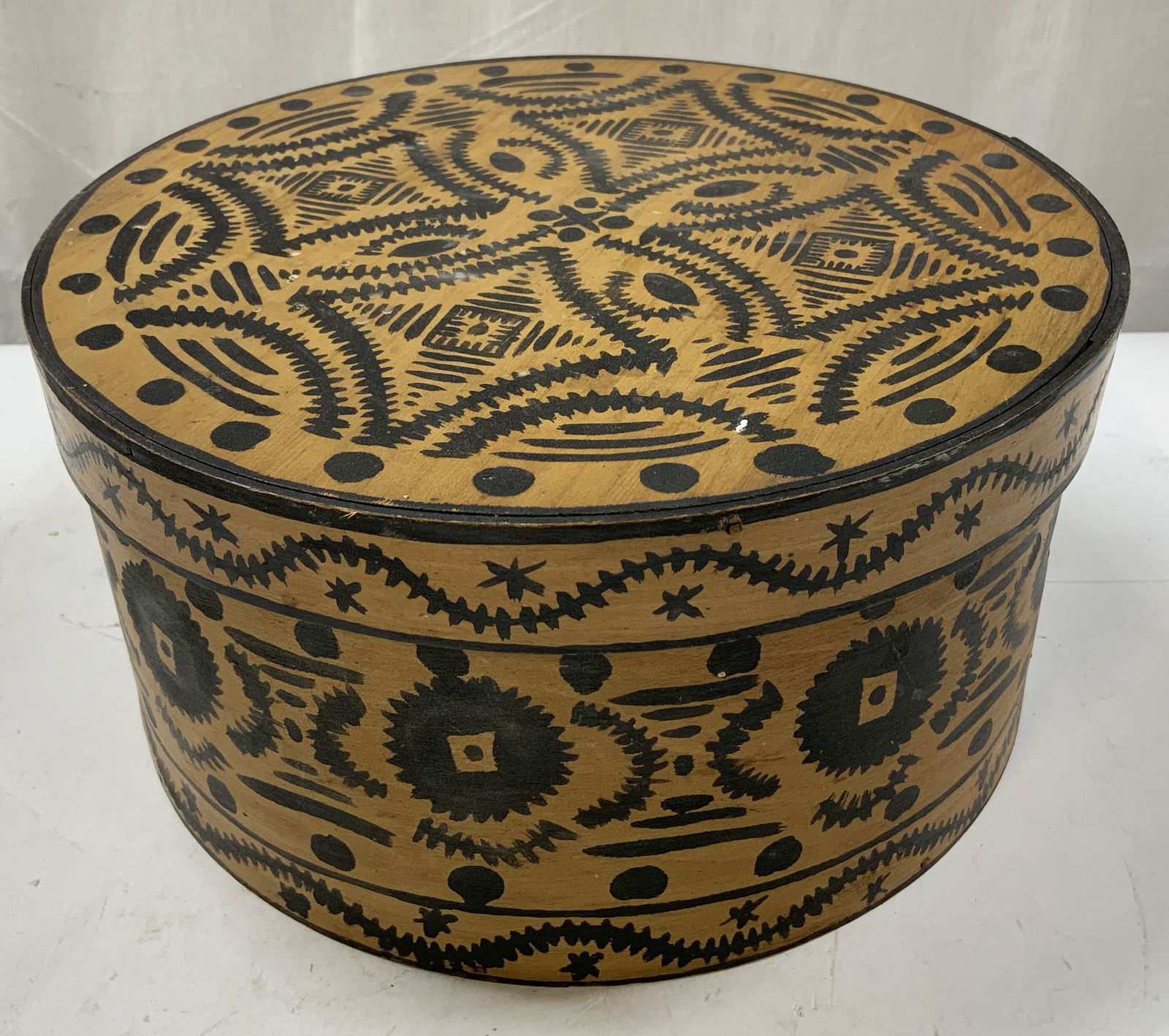 Folk Art Bentwood Box W Hand Painted Blck Motifs: Round bentwood box w a fitted lid, featuring hand-painted black geometric motifs. Lid has dotted borders. Surface wear consistent to age, use & exposure. Measurements: length 9.5in x width 9.5in x hei