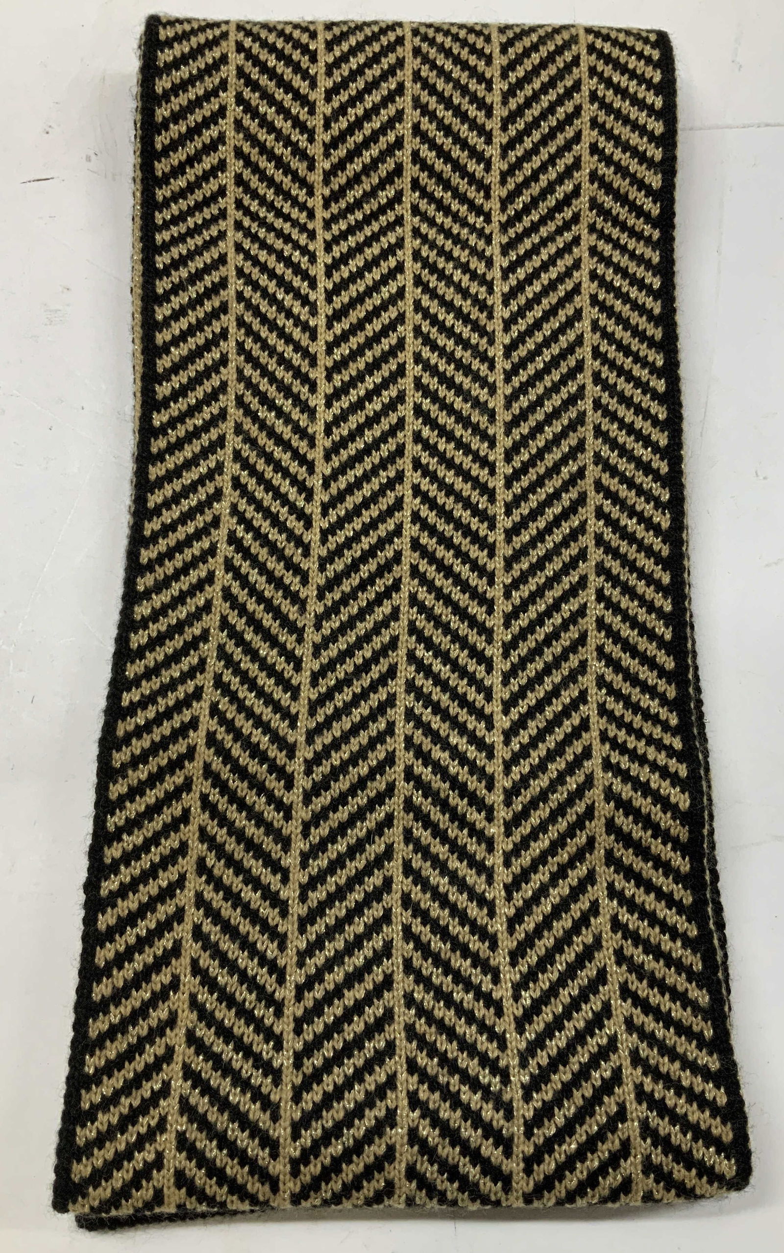 Calvin Klein Black & Tan Chevron Knit Scarf: Scarf is 94% acrylic & 4% polyester. Features black & tan tones w a chevron print. Surface wear consistent to age, use & exposure. Signed & marked. Reads, CALVIN KLEIN. 94% ACRYLIC. 4% POLYESTER. Surf
