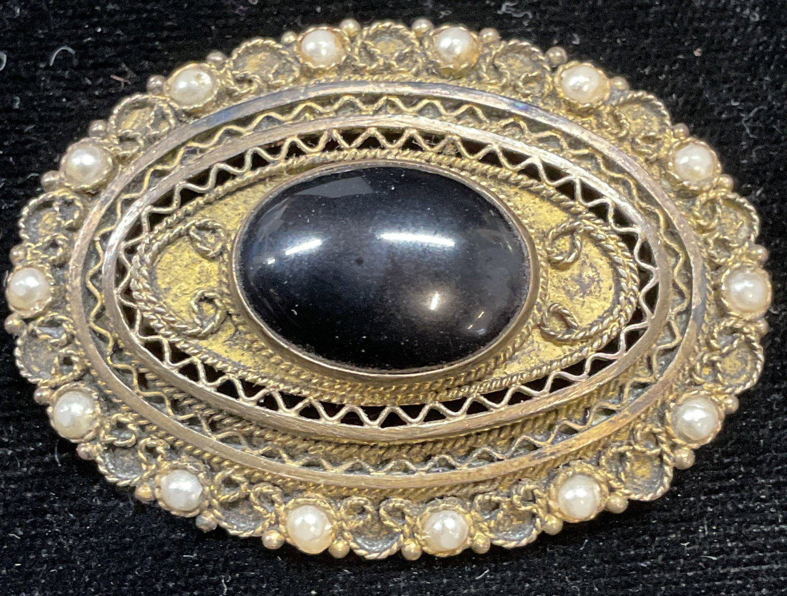 Vtg Sterling Silver Onyx Filigree Brooch Israel: Vintage gold plated sterling silver filigree brooch with onyx cabochon and seed pearl accents. Marked sterling. Made in Israel. Measures approx 1.25 x 2 inches. Total weight 11.3 grams. Some scratchin