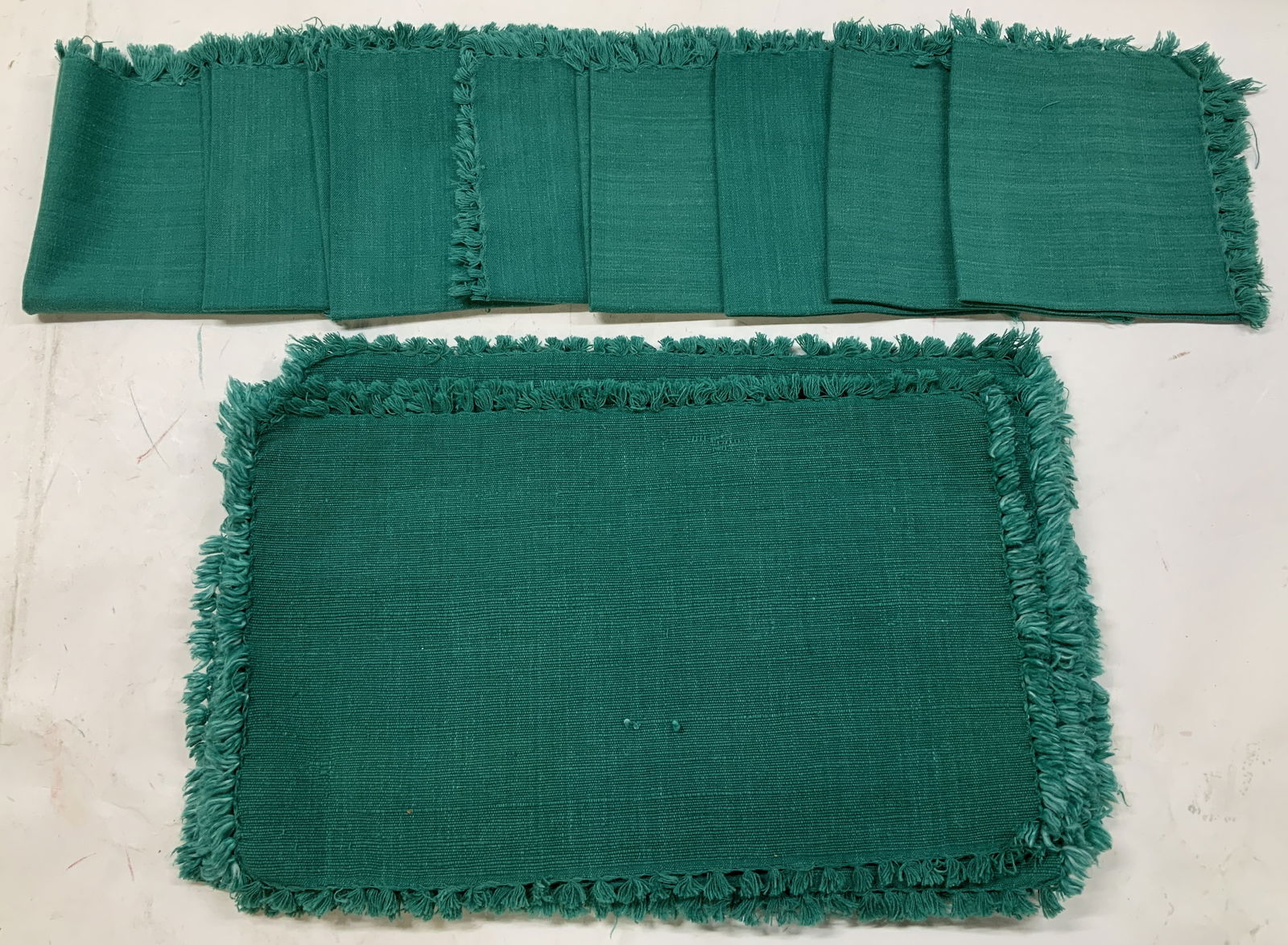 Set 16 Green Fringed Napkins & Placemats: Lot includes, 8 napkins & 8 placemats. Pieces are green toned w fringed ends. Appears to be cotton material. Surface wear consistent to age, use & exposure. Measurements: length 17.5in x width 11in. G