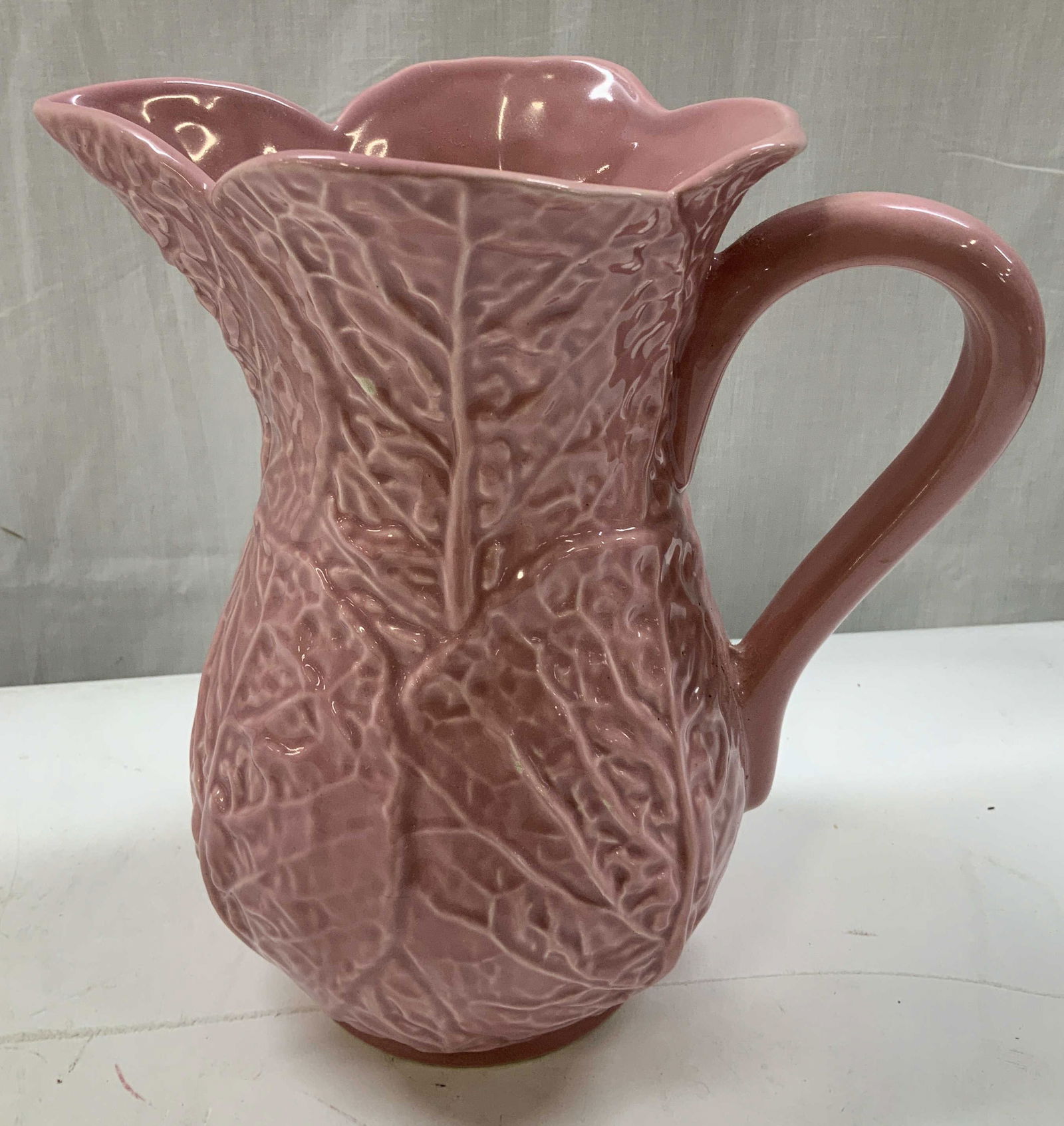 Subtil Pink Embossed Cabbage Pitcher PORTUGAL: Pitcher is ceramic & depicts an intricate, embossed pattern. Piece is pink toned & features a scalloped rim. Glossy finish. Signed & marked on underside. Reads, SUBTIL. PORTUGAL. P232. Surface wear co