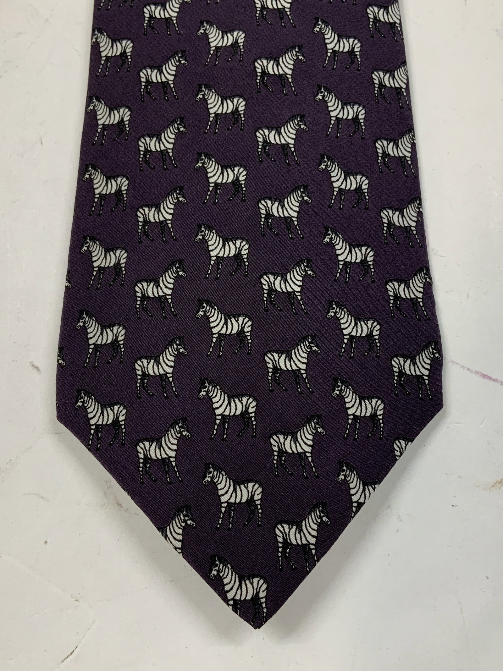 Rue de la Paix Purple Zebra Motif Silk Necktie: Necktie is silk material & features a dark purple background w a repeating pattern of zebra motifs. Signed & marked. Reads, RUE DE LA PAIX. 100% Silk. Surface wear consistent to age, use & exposure. M
