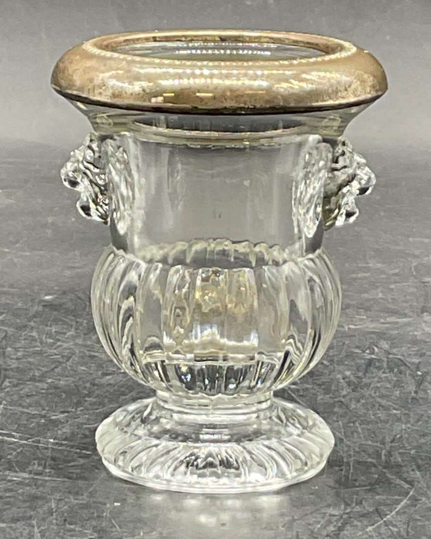 Antique Silver Plated Glass Urn: Antique silver plated glass urn. Silver plated rim and circular base. Ribbed pattern on body with lion head accents on the sides. Measures ht approx 3 inches diam approx 3 inches. Some surface wear co