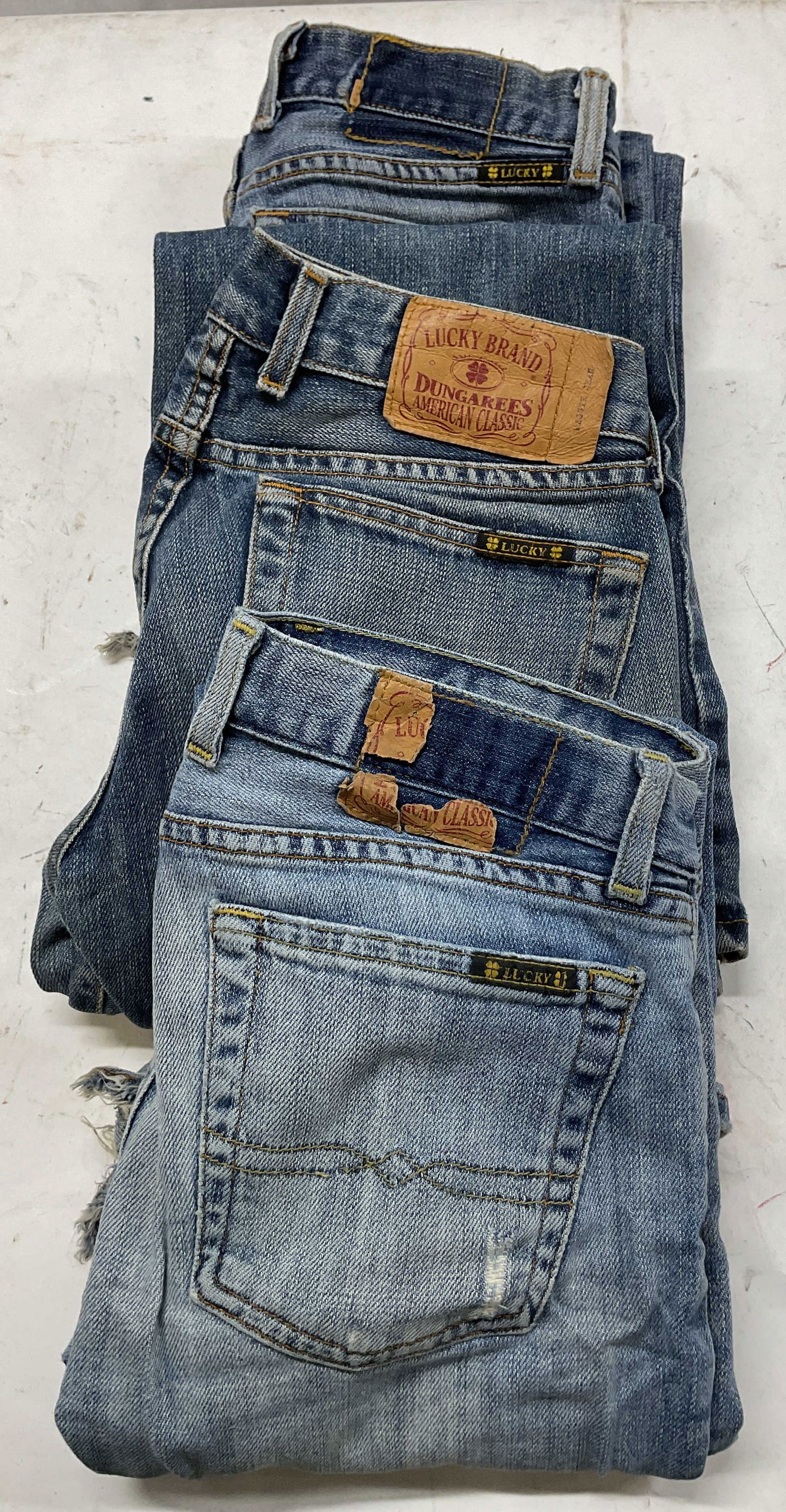 Lot 3 Lucky Brand Jeans USA: Lot of 3 pairs of Lucky Brand jeans. All size 4. All made in USA. All cotton material. Vary from light to dark washes. Some blemishes and ripping observed. Some wear consistent with use and exposure.