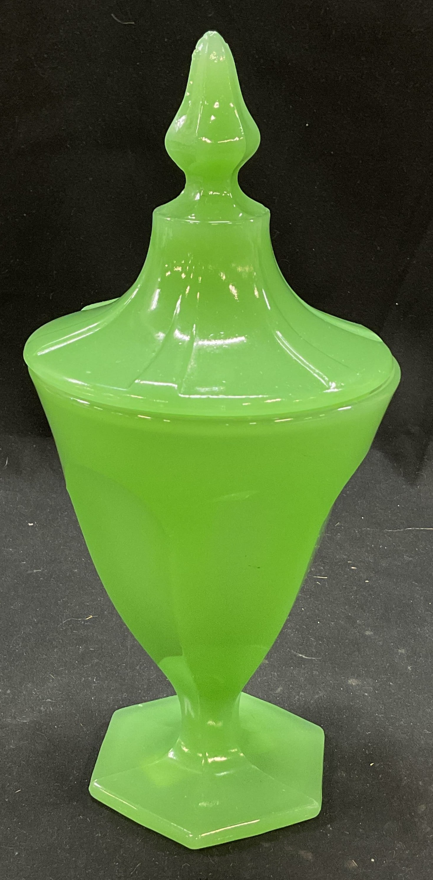 Vintage Glass Pedestal Bowl W Lid: Vintage green glass pedestal bowl with lid. Paneled design on body and lid. Hexagonal footed base. Lid has pointed finial. Appears to be a lighter green. Measures ht approx 9 1/2 inches diam approx 5 