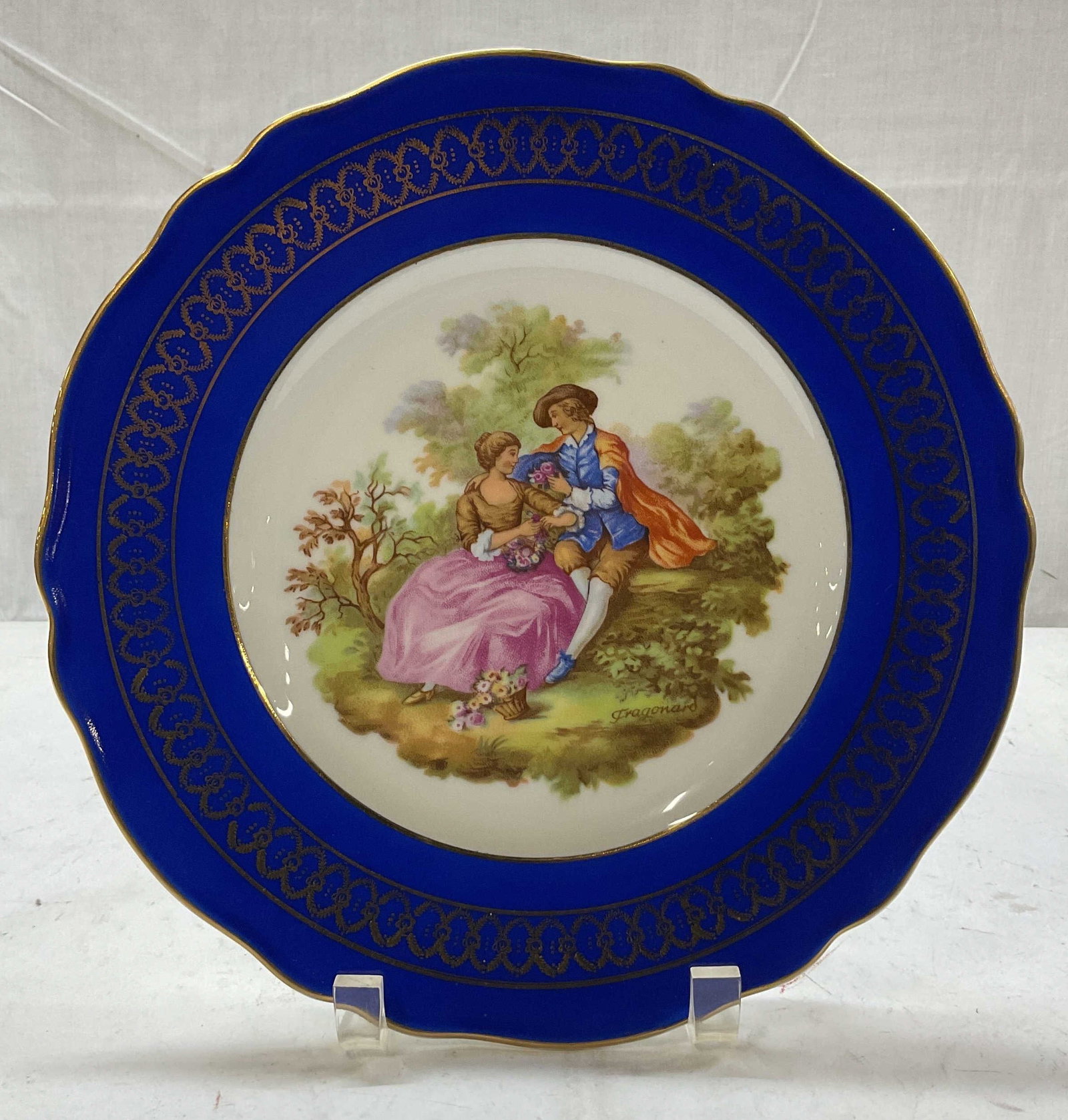 Vintage JKW Fragonard Porcelain Plate Germany: Vintage JKW Fragonard porcelain plate. Made in Western Germany. Marked on underside. Underside reads as follows Fine Porcelain JKW 1930 Western Germany. Circular plate with footed base. Blue rim with 