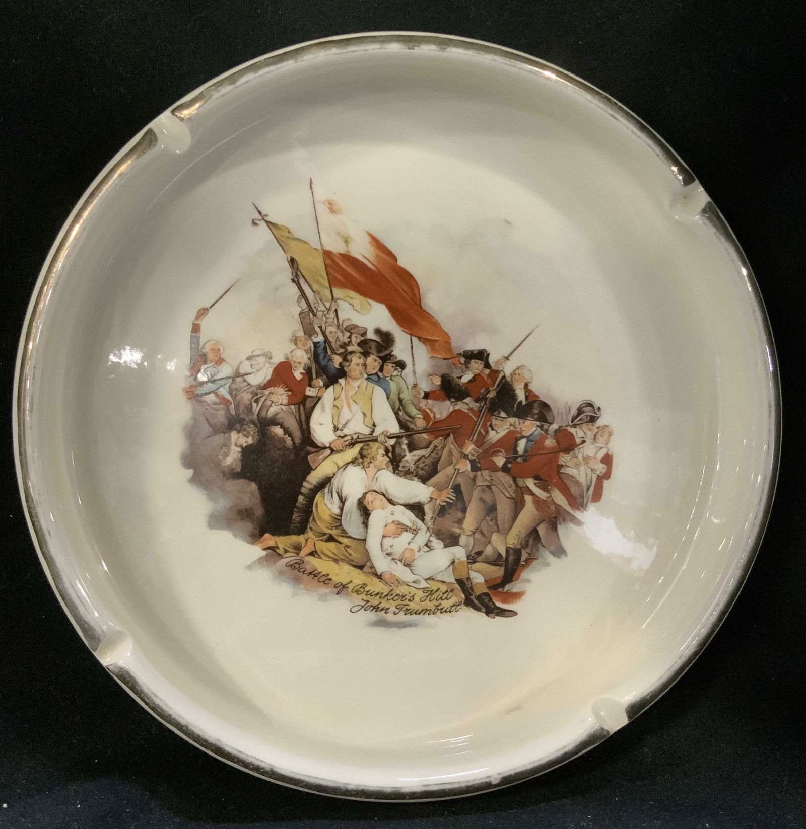 Battle of Bunkers Hill Trumbull Ceramic Ashtray: Ceramic ashtray featuring a depiction of the painting, The Battle of Bunkers Hill, June 17, 1775, by John Trumbull. Features 4 raised rim with indentations to hold cigarettes. Surface wear consistent