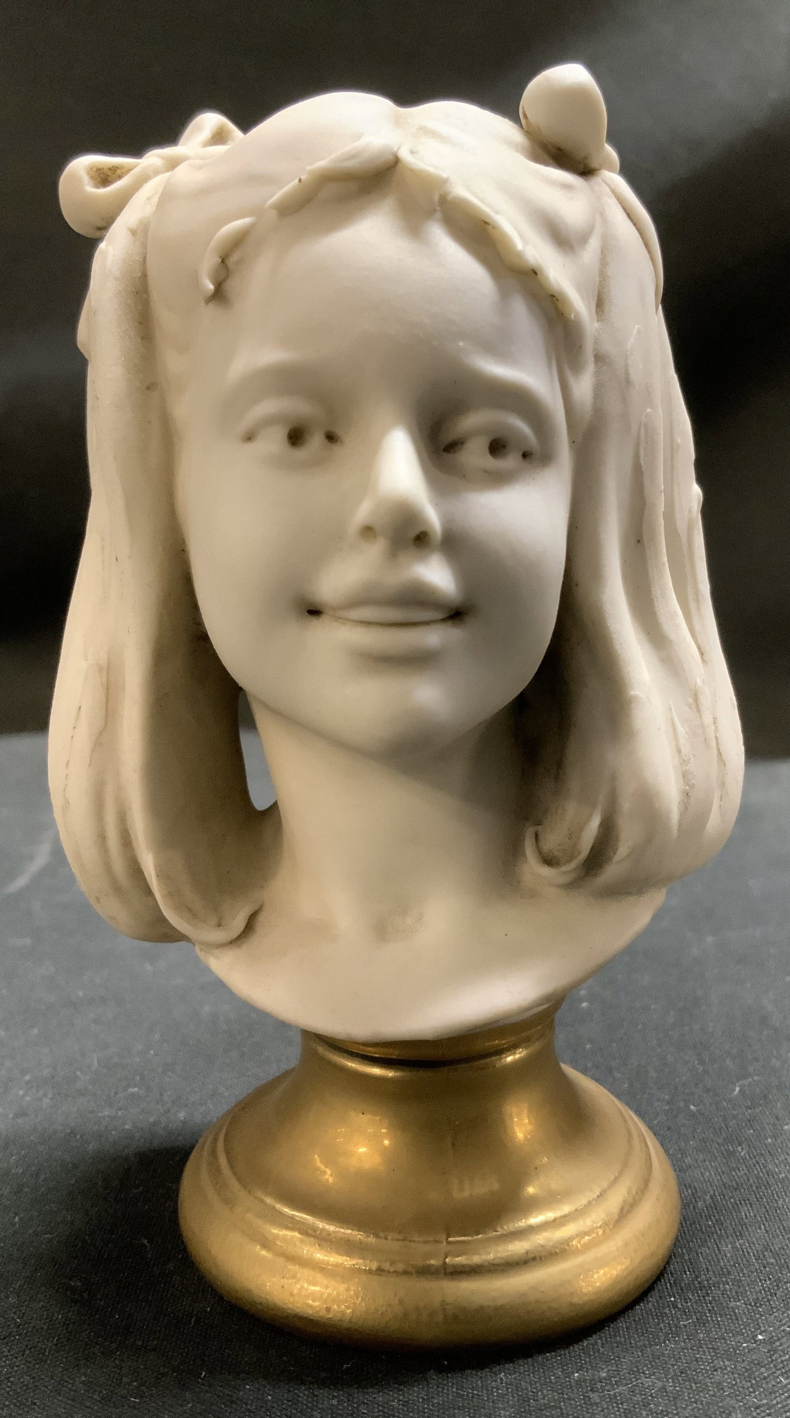 Vntg Friade Benacchio Porcelain Girl Bust: Girl bust is made of white porcelain & features a gold-toned base. Intricate & textured details. Bow details in hair. Backside of bust reads, BENACCHIO. Surface wear consistent to age, use & exposure.