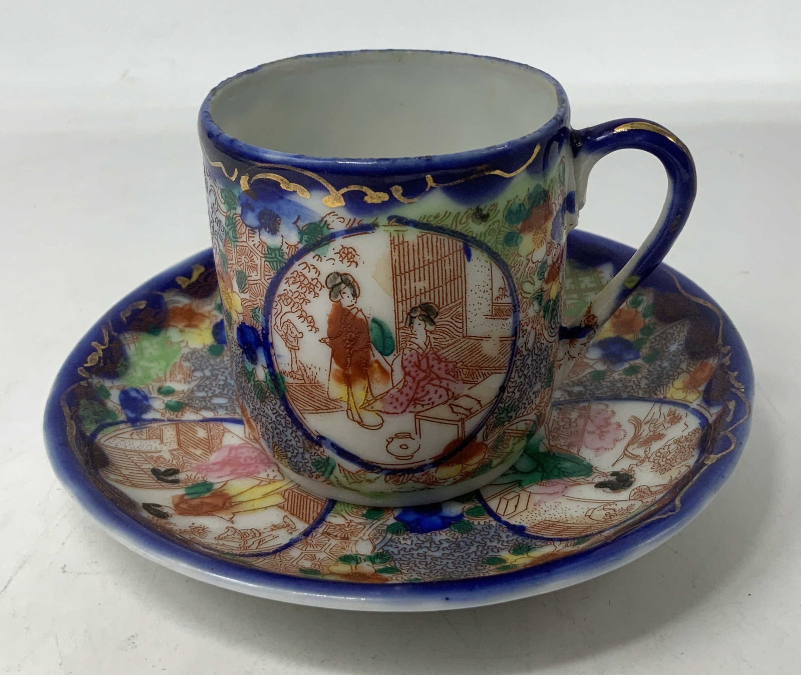 Vntg Japanese Cobalt Blue Scenic Teacup & Saucer: Vintage Japanese hand-painted teacup and saucer set. Features small, colorful figures in circular motifs. Floral motifs & cobalt blue trims. Porcelain material. Surface wear consistent to age, use & e