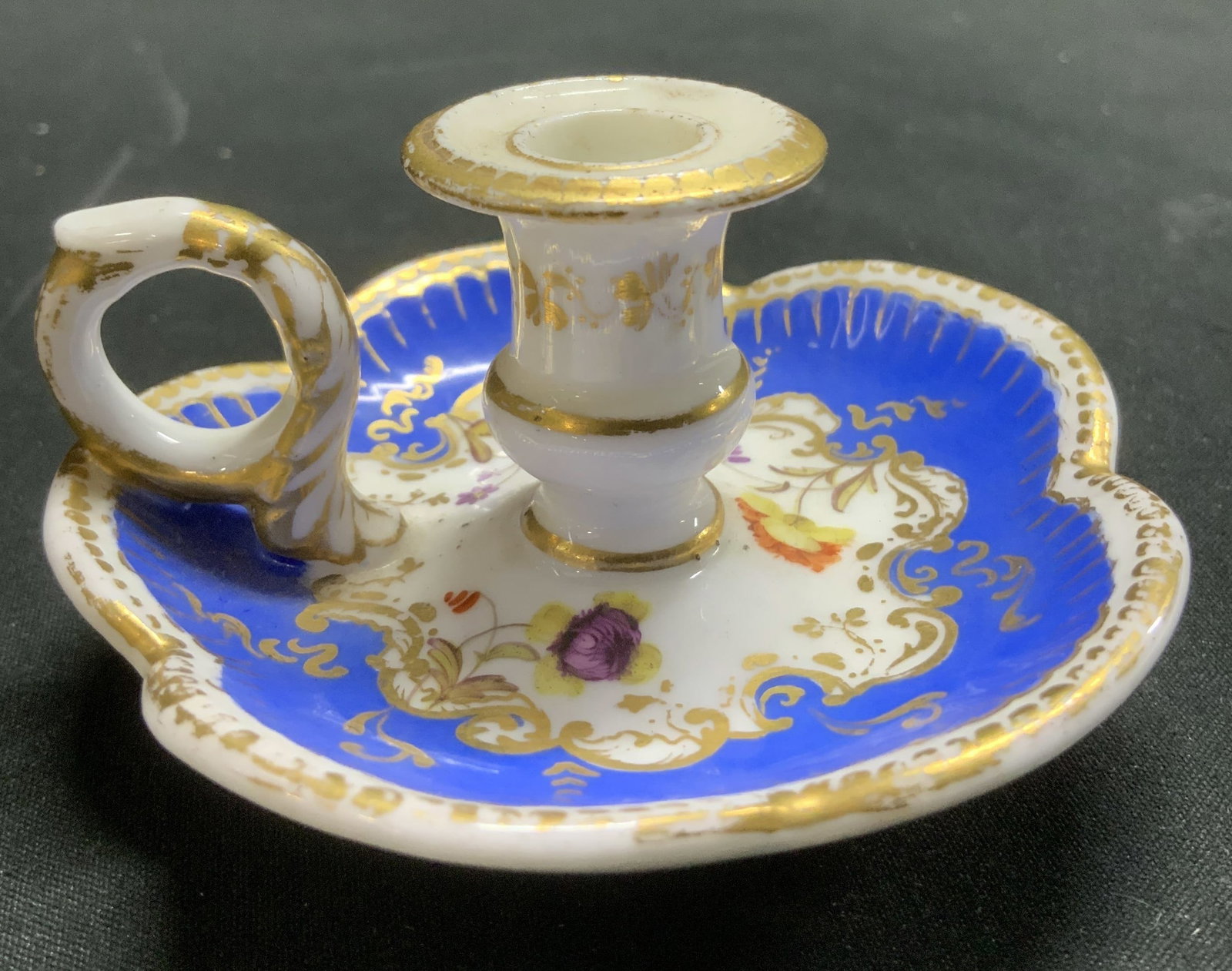 Antique Porcelain Miniature Gilt Chamberstick: Chamberstick is porcelain & feature a scalloped, ornate base & small loop handle. Blue & gilt accents. Floral motifs. Appears to be antique, possible vintage. Surface wear consistent to age, use & exp