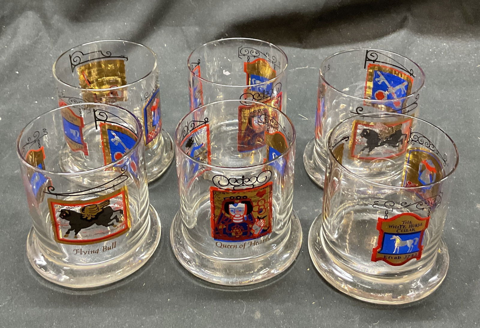 Set 6 White Horse Cellar Whiskey Glasses: Set of 6 White Horse Cellar whiskey glasses. Features designs including The Five Alls, Queen of Hearts, The Cross Keys, and more. Motifs including keys, books, woman figure, and more. Measures ht appr