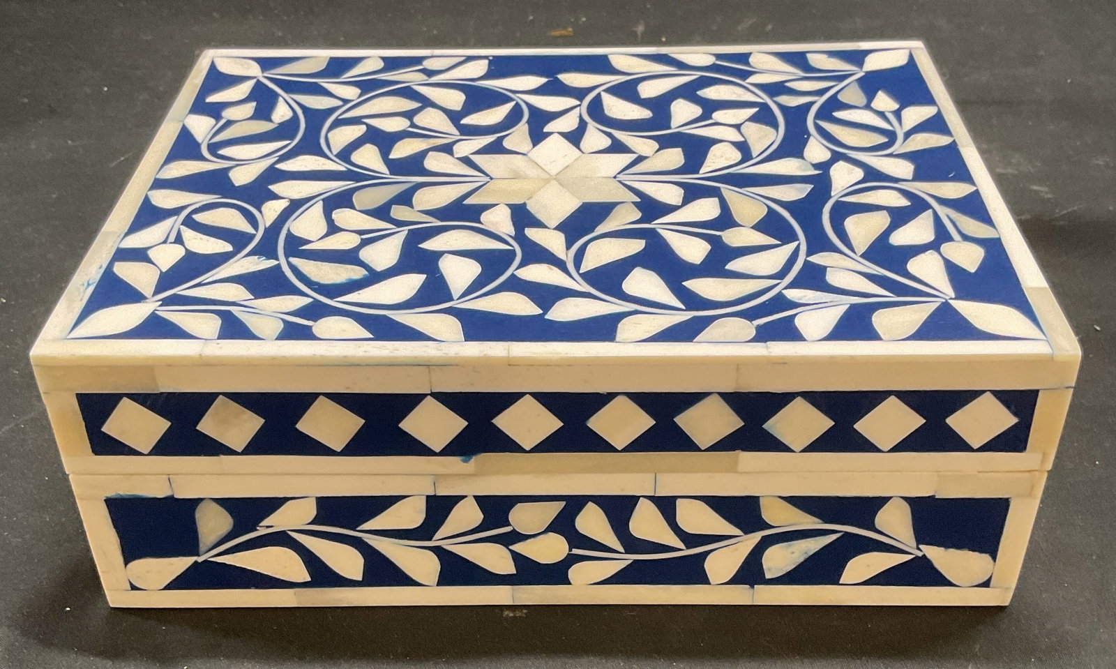 Inlaid Bone Blue Floral Dresser Box: Dresser or jewelry box with lid. Wood with bone overlay in blue and white. Geometric floral pattern. Measures approx 8 x 6 x 2.75 inches. Some scratching. Bone overlay box, floral box, dresser box, je