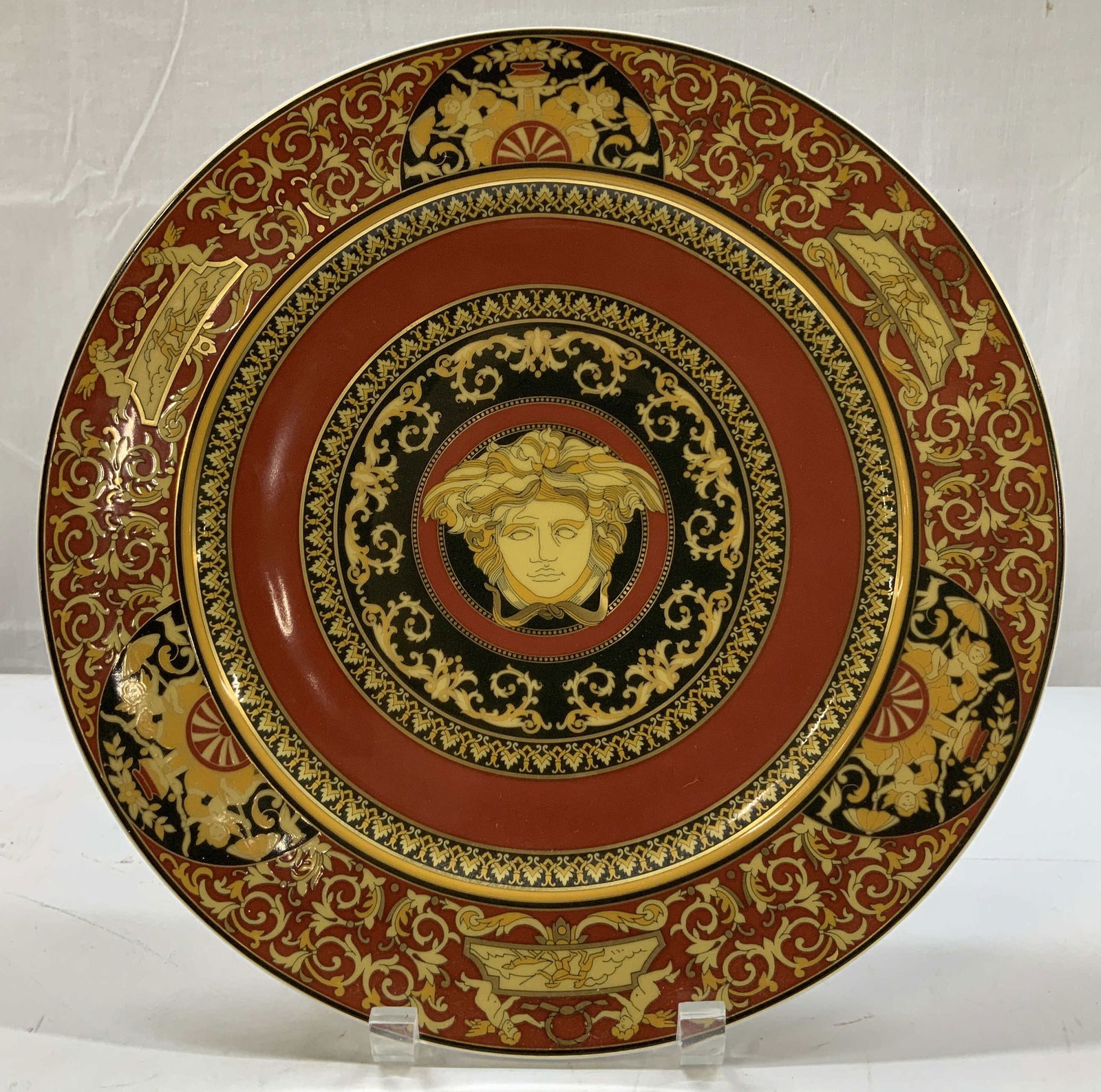 Versace Rosenthal Medusa Porc Service Plate GER: Versace by Rosenthal Medusa service plate. Plate is porcelain & features a neoclassical design. Center of plate features Medusa head & is surrounded by black/gold scroll w angel motifs. Signed & marke