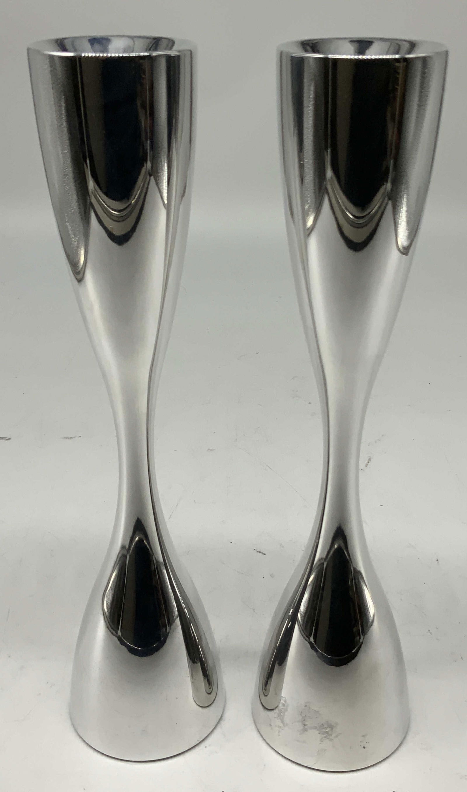 Pair 2005 Nambe Karim Rashid Flare Candlesticks: Candlesticks are made of metal alloy & features a polished silver toned finish. Hourglass shape. Signed & marked on underside. Reads, NAMBE 6310. 2005. KARIM RASHID. Surface wear consistent to age, us