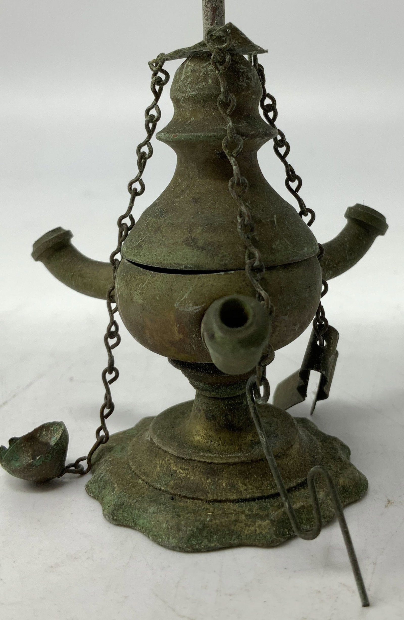 Antique Brass Florentine Oil Lamp: Florentine oil lamp is brass material & is antique. Features three wicks & chains. A tall rod with a triangular carrying handle extends upwards. Surface wear consistent to age, use & exposure. Measure